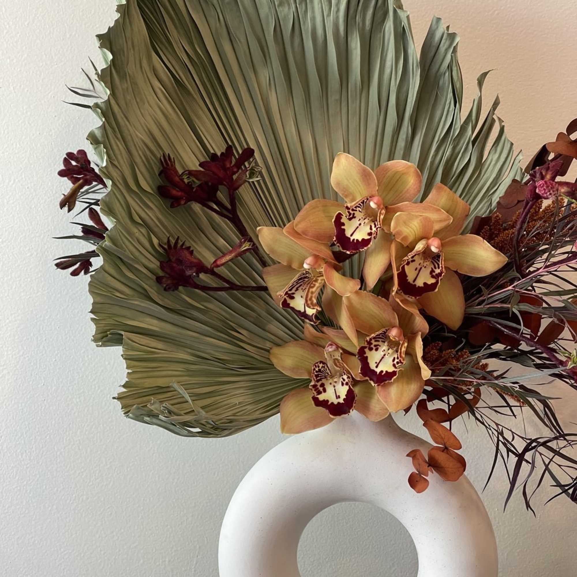 Orchid arrangement with a large fan-shaped leaf in a white ring vase, photo 2 of 3