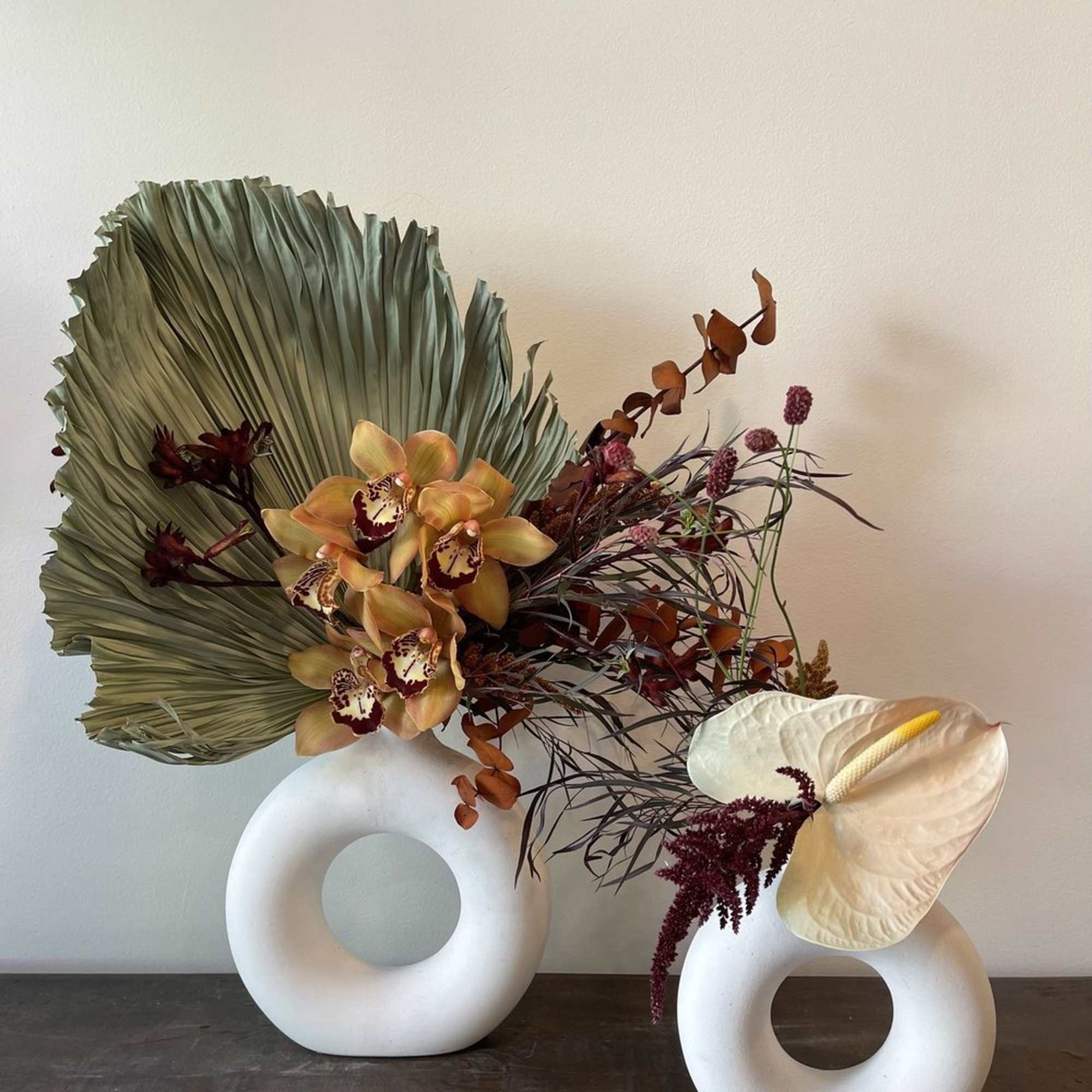 Modern floral arrangement with orchids and anthurium in white ring vases