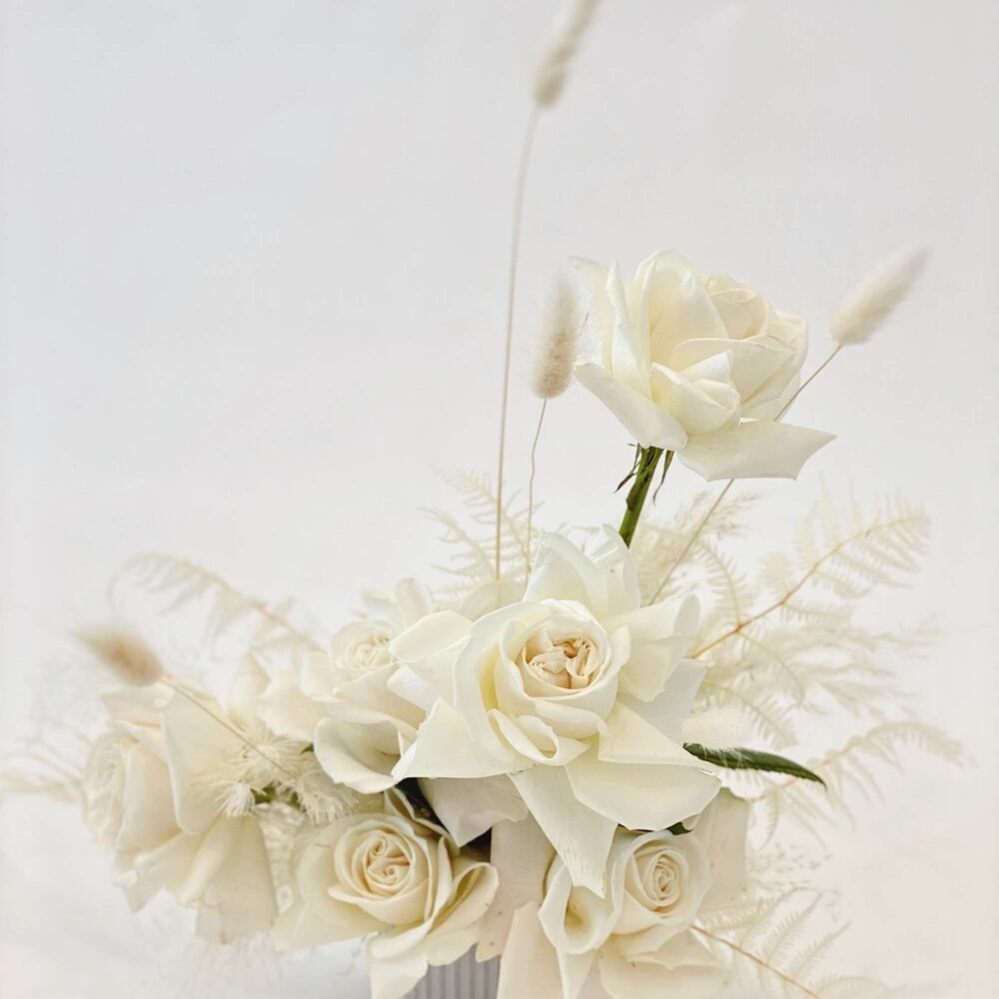 White rose arrangement in a small ribbed container