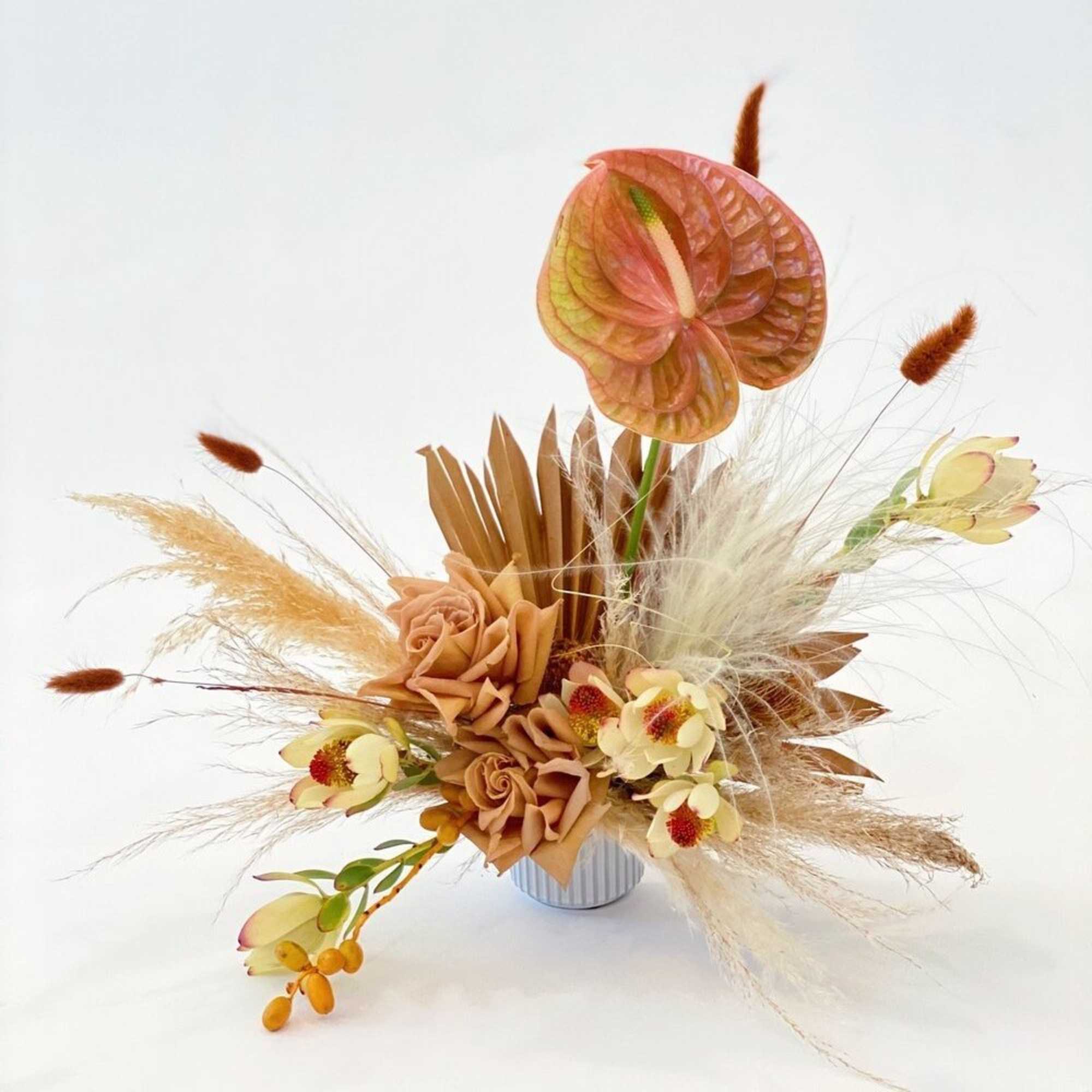 Arrangement with peach flowers and dried grasses in a small vase