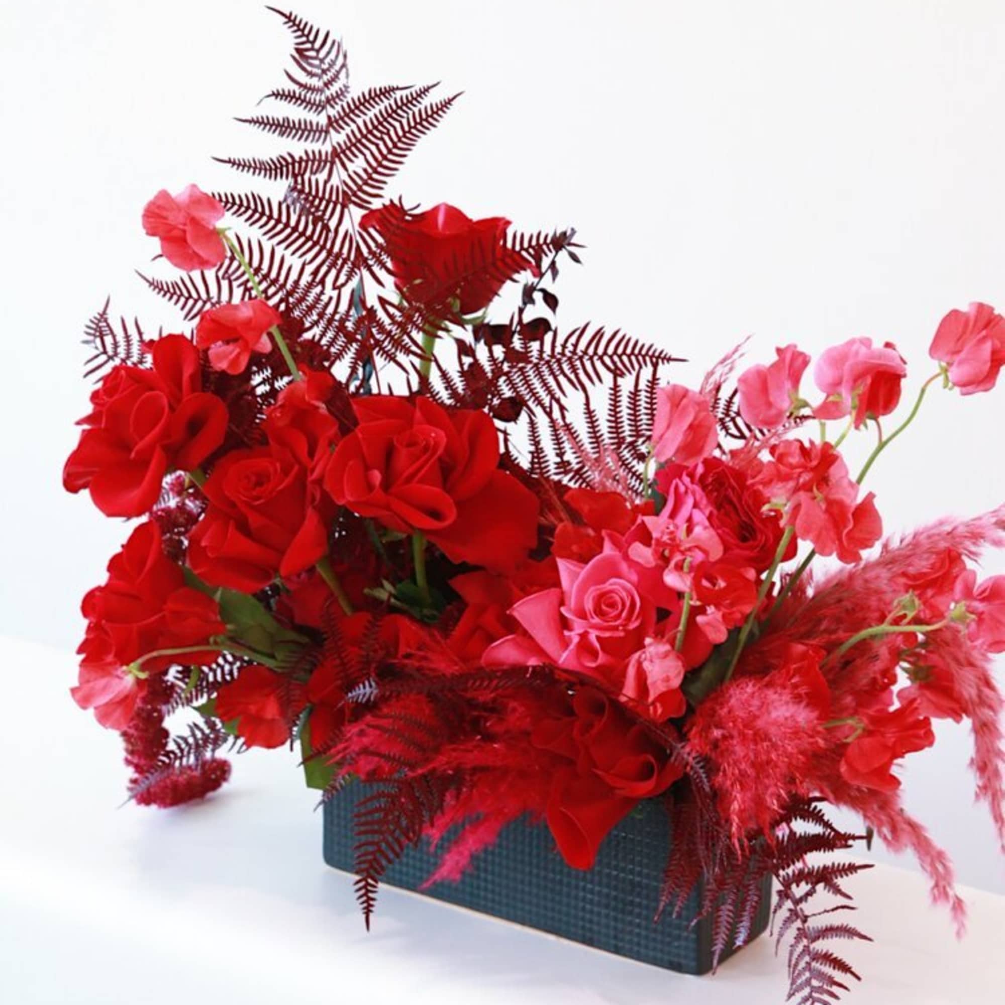 Red and pink rose arrangement in a rectangular vase
