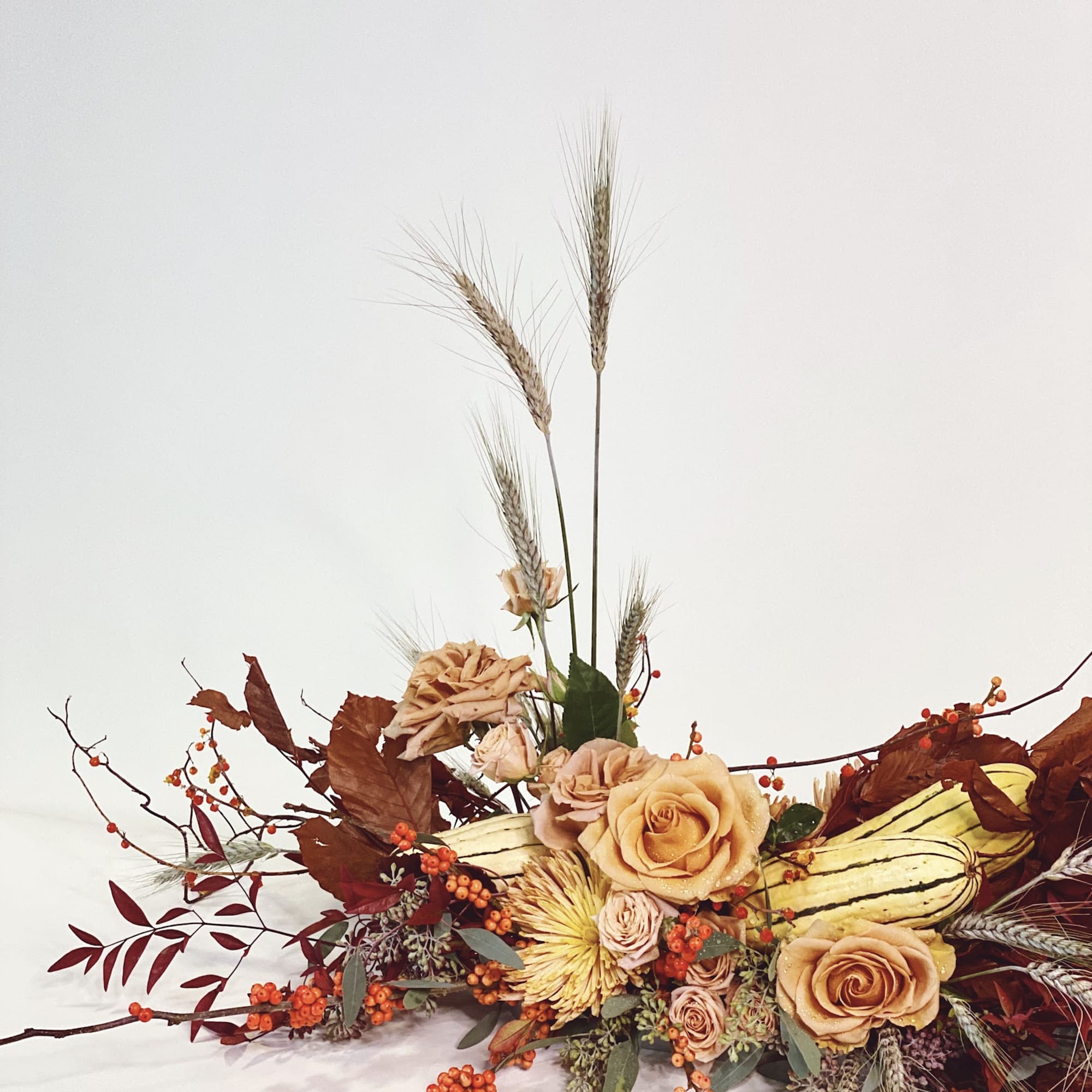 Autumn floral arrangement with peach roses and wheat stalks