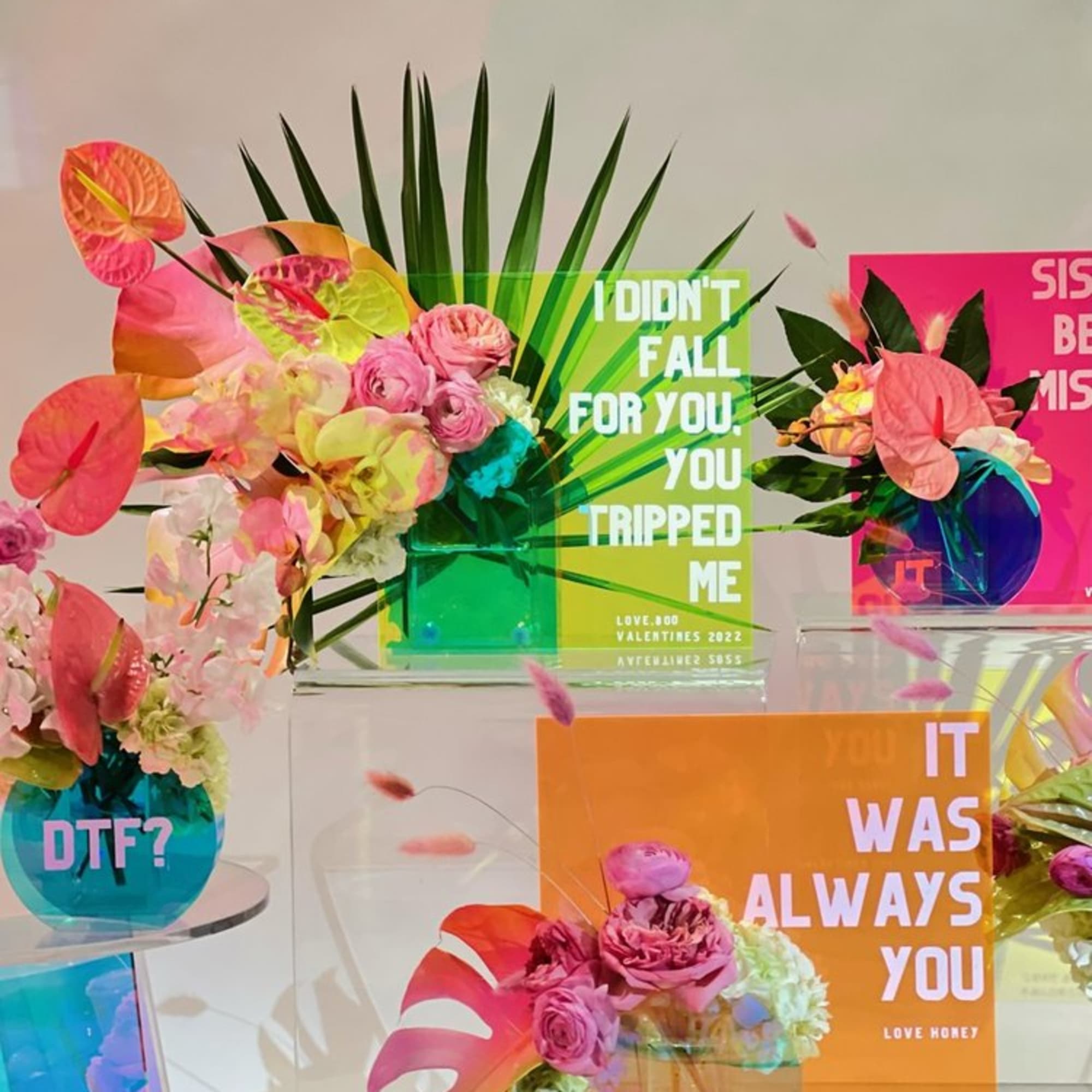 Colorful floral arrangements with tropical leaves and pink flowers in clear vases