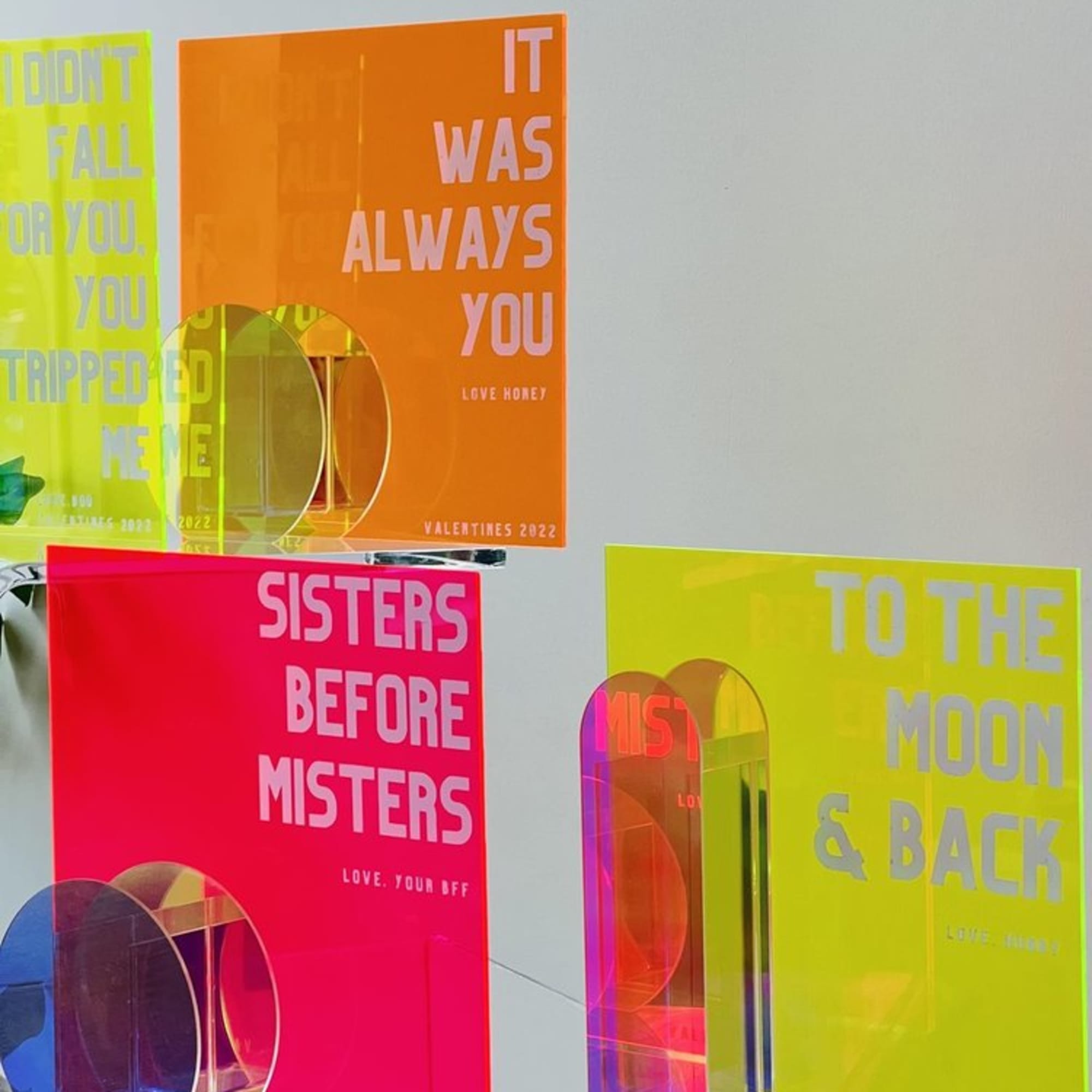 Neon acrylic Valentine cards with bold text on a shelf