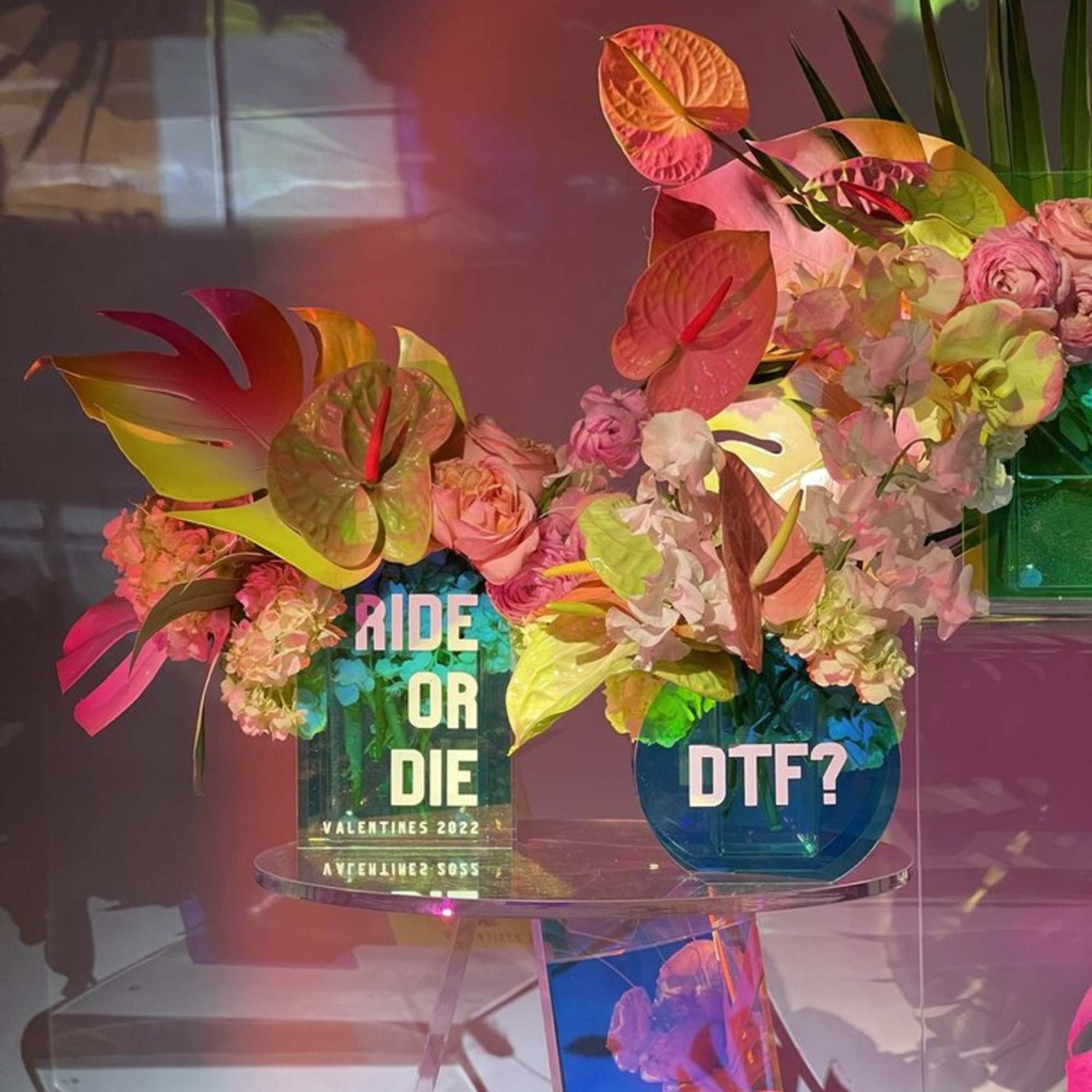 Two colorful floral arrangements in glass vases on a clear table