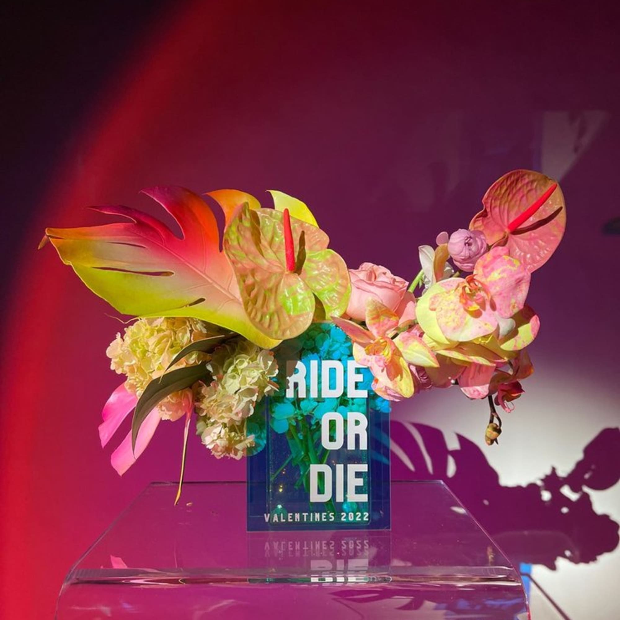 Tropical floral arrangement with an acrylic sign reading "BRIDE OR DIE"