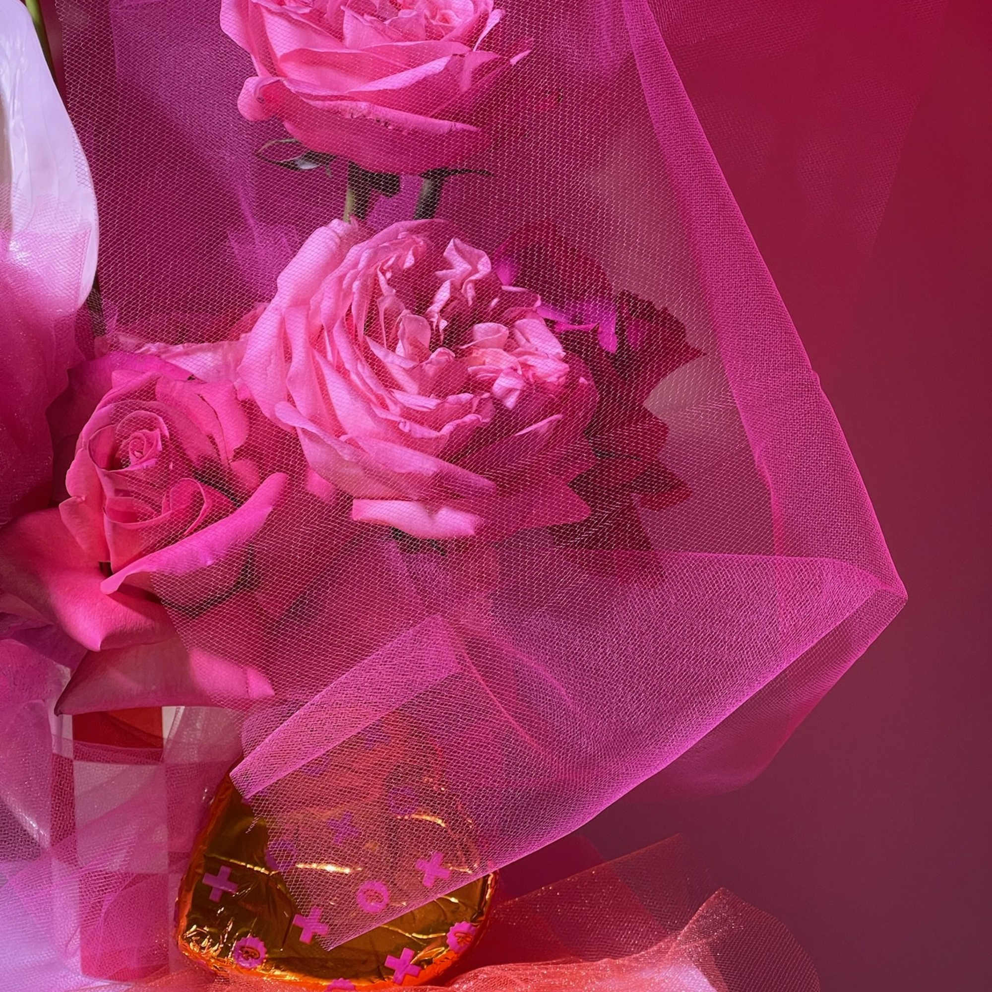 Pink roses wrapped in sheer pink mesh with a gold vase