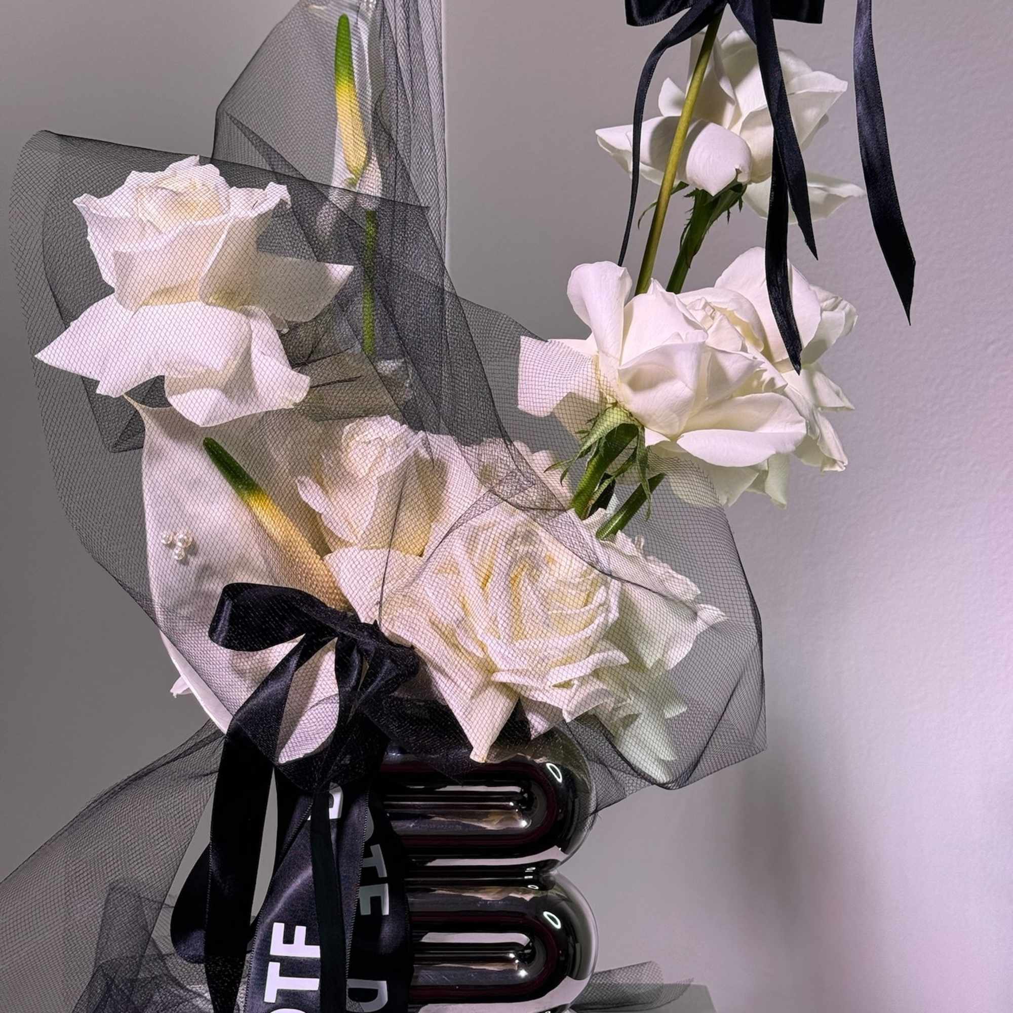 White roses wrapped in black mesh with black ribbons