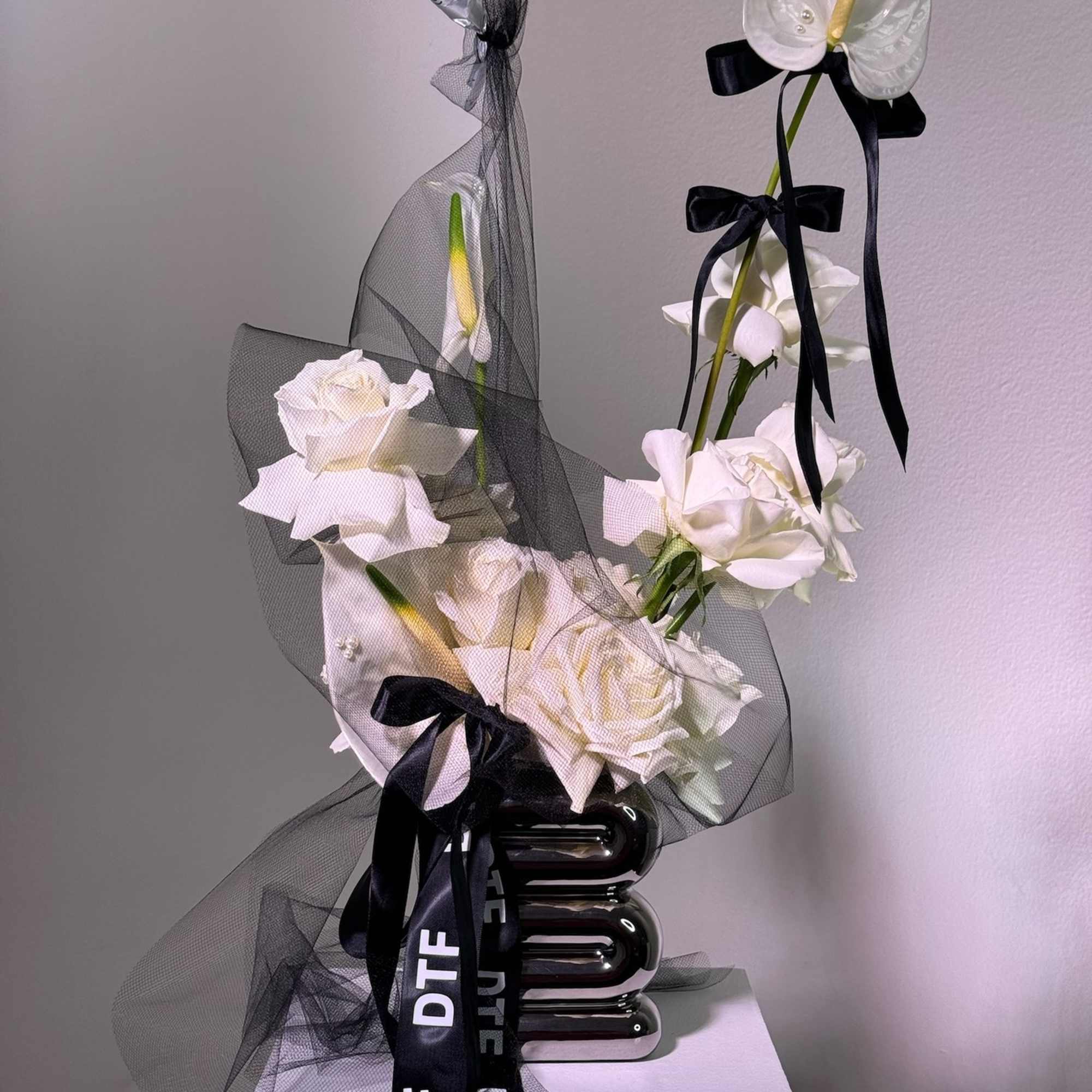 White roses and anthuriums wrapped in black mesh with ribbon