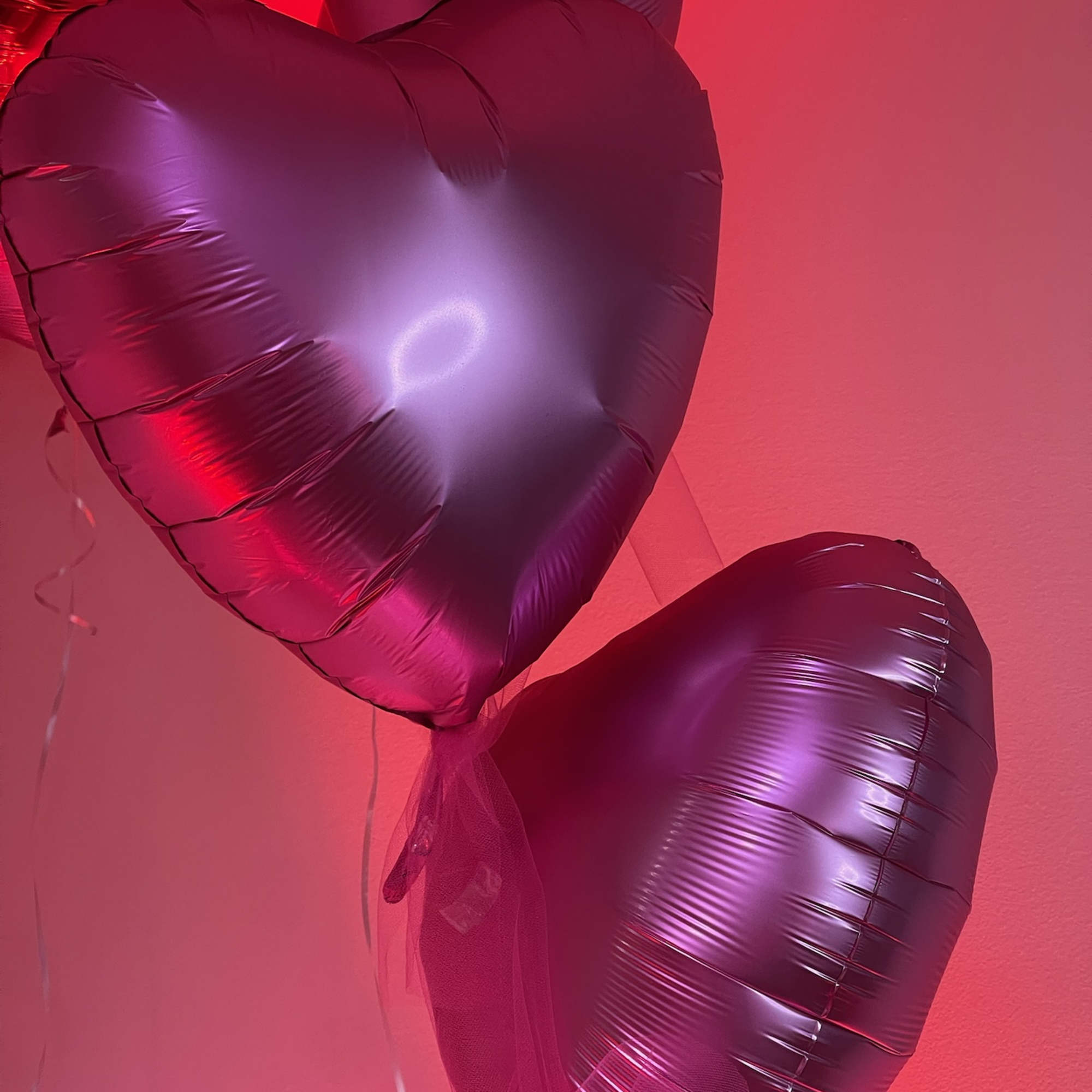 Heart-shaped pink balloons against a pink wall