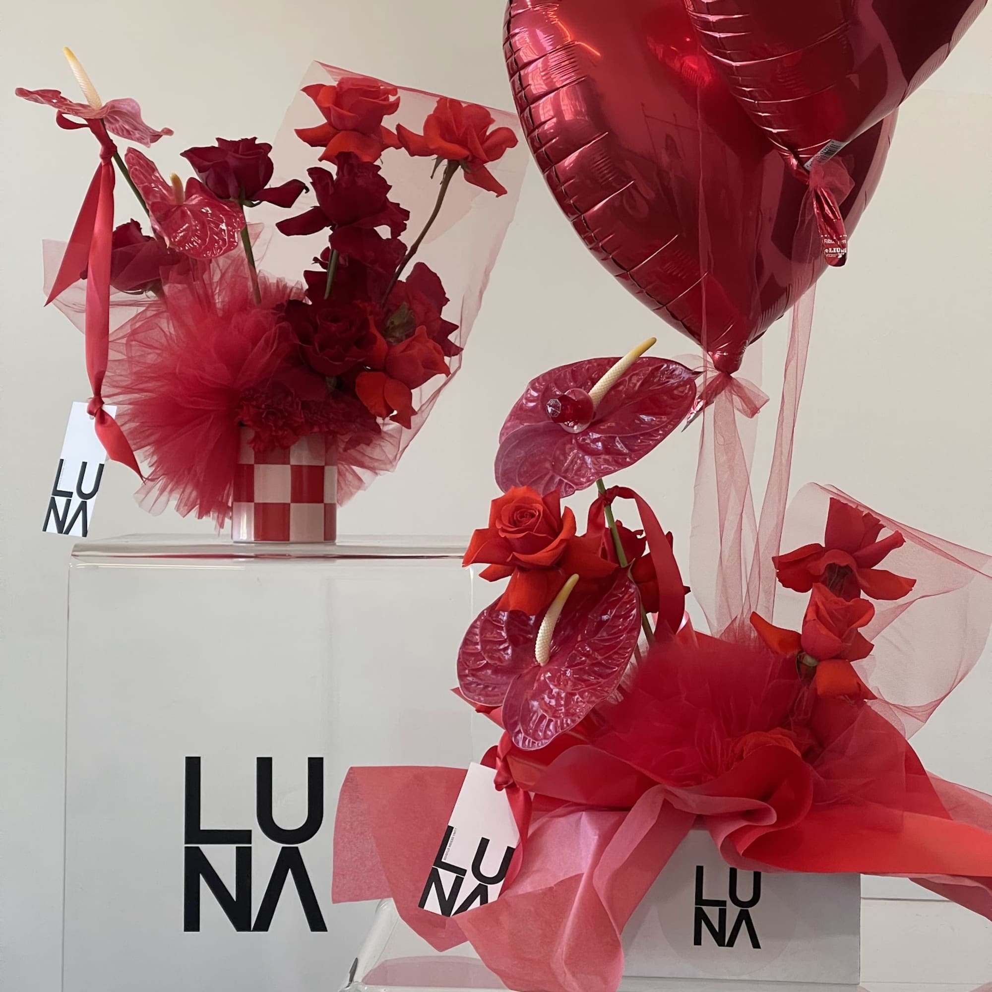 Red rose arrangements with heart-shaped balloons and pink wrapping