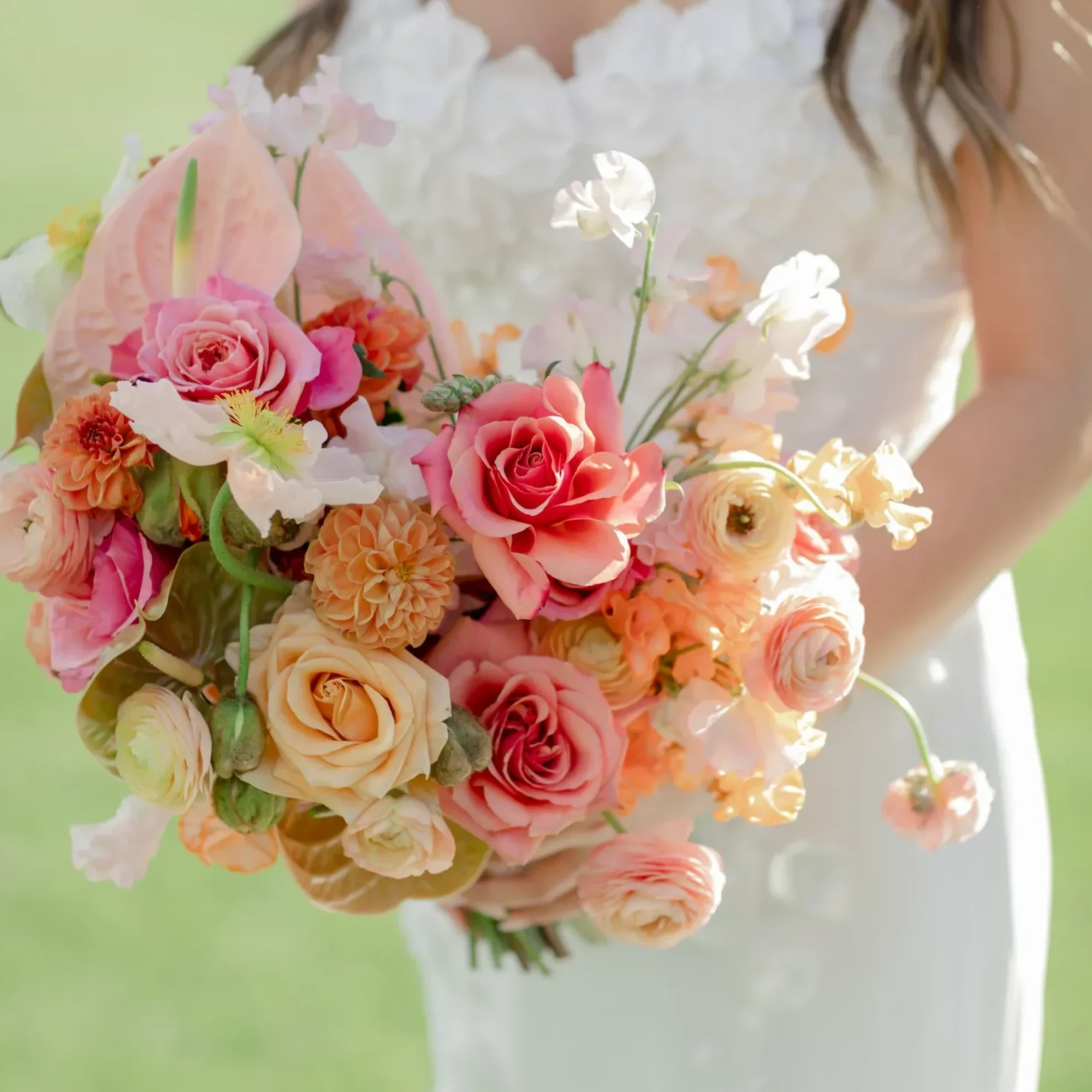 Bride holding a pastel bouquet of roses, ranunculus, and orchids