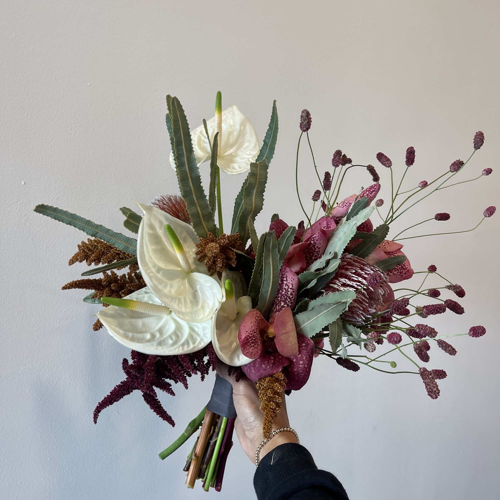 Handheld bouquet with white anthuriums and pink protea-like blooms