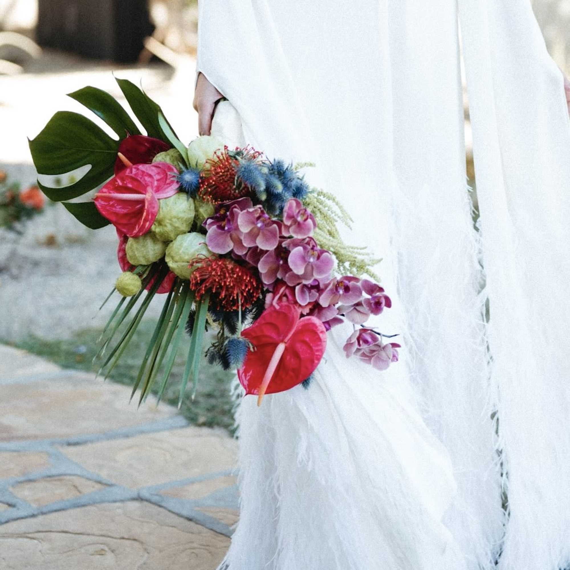 Bride holding a tropical bouquet with pink anthuriums and orchids, photo 3 of 3