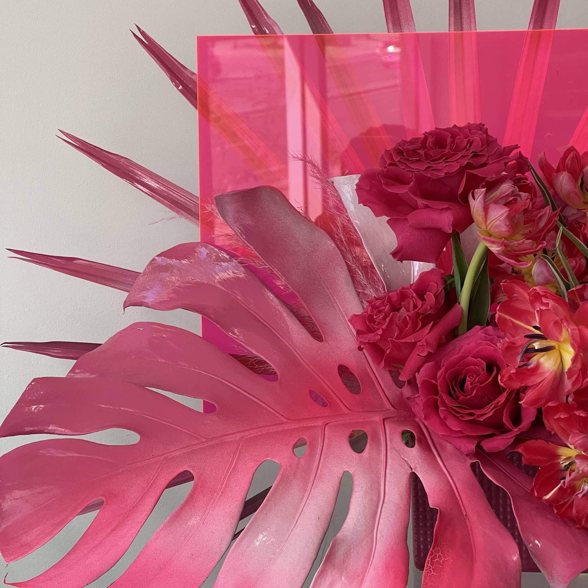 Hot pink floral arrangement with roses and tropical leaves