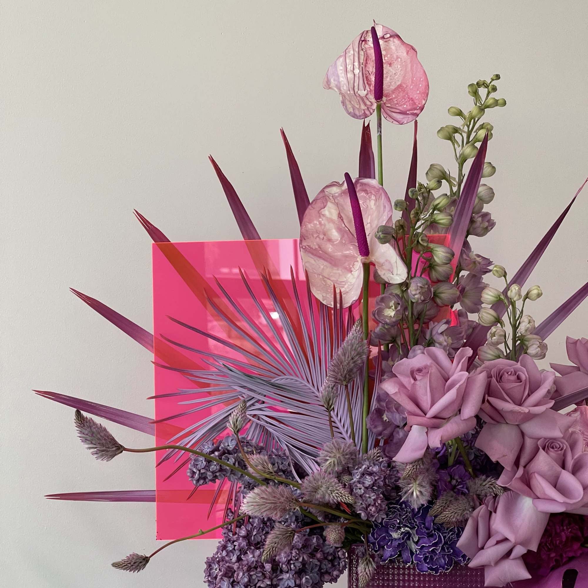 Pink and purple floral arrangement with roses and anthuriums in a magenta vase