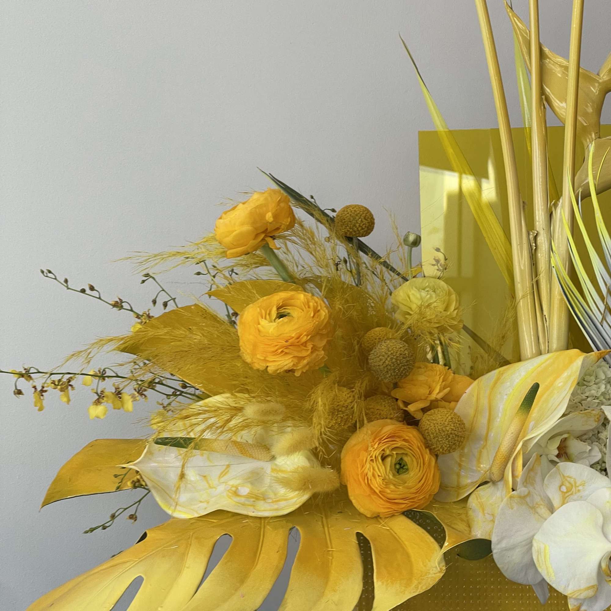 Yellow floral arrangement with white orchids and tall decorative stems