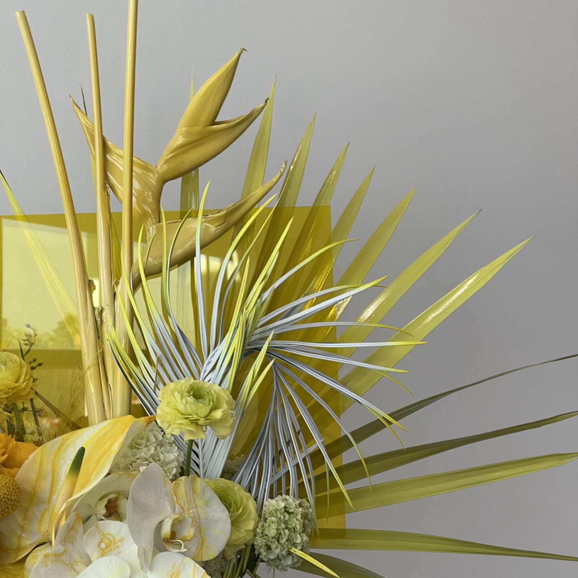 Yellow floral arrangement with white orchids and tropical leaves