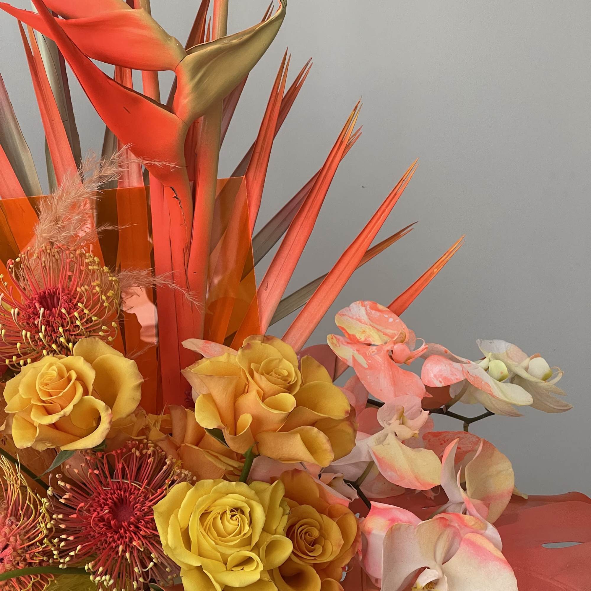 Tropical bouquet with yellow roses, pink orchids, and orange bird-of-paradise