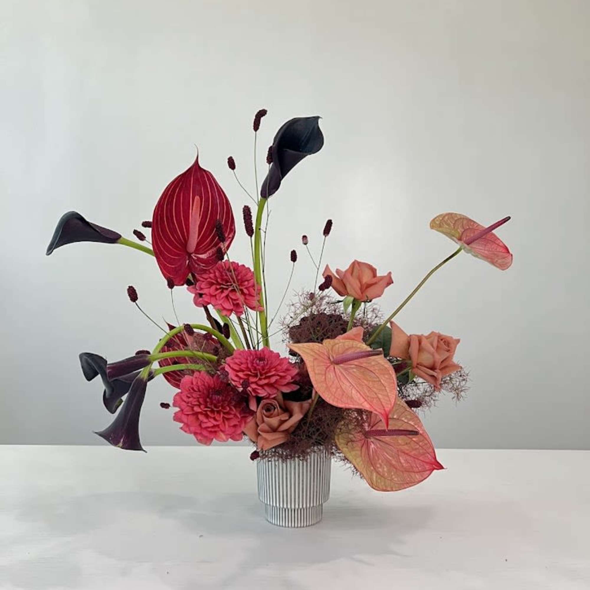 Modern floral arrangement with pink and peach blooms in a striped vase