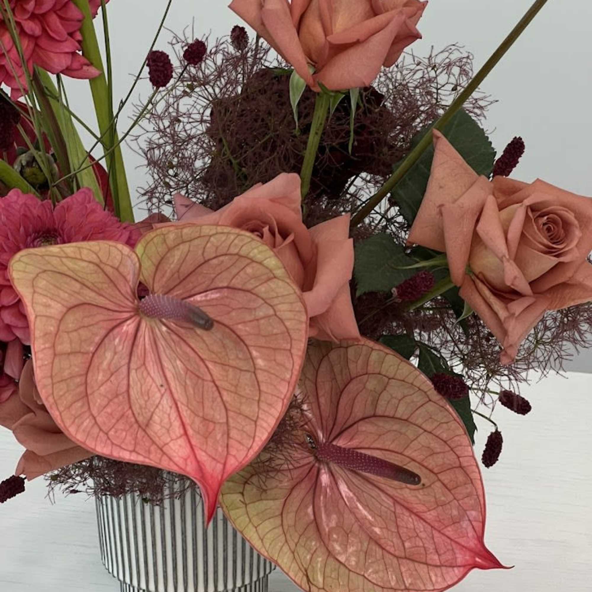 Pink roses and anthuriums in a striped vase