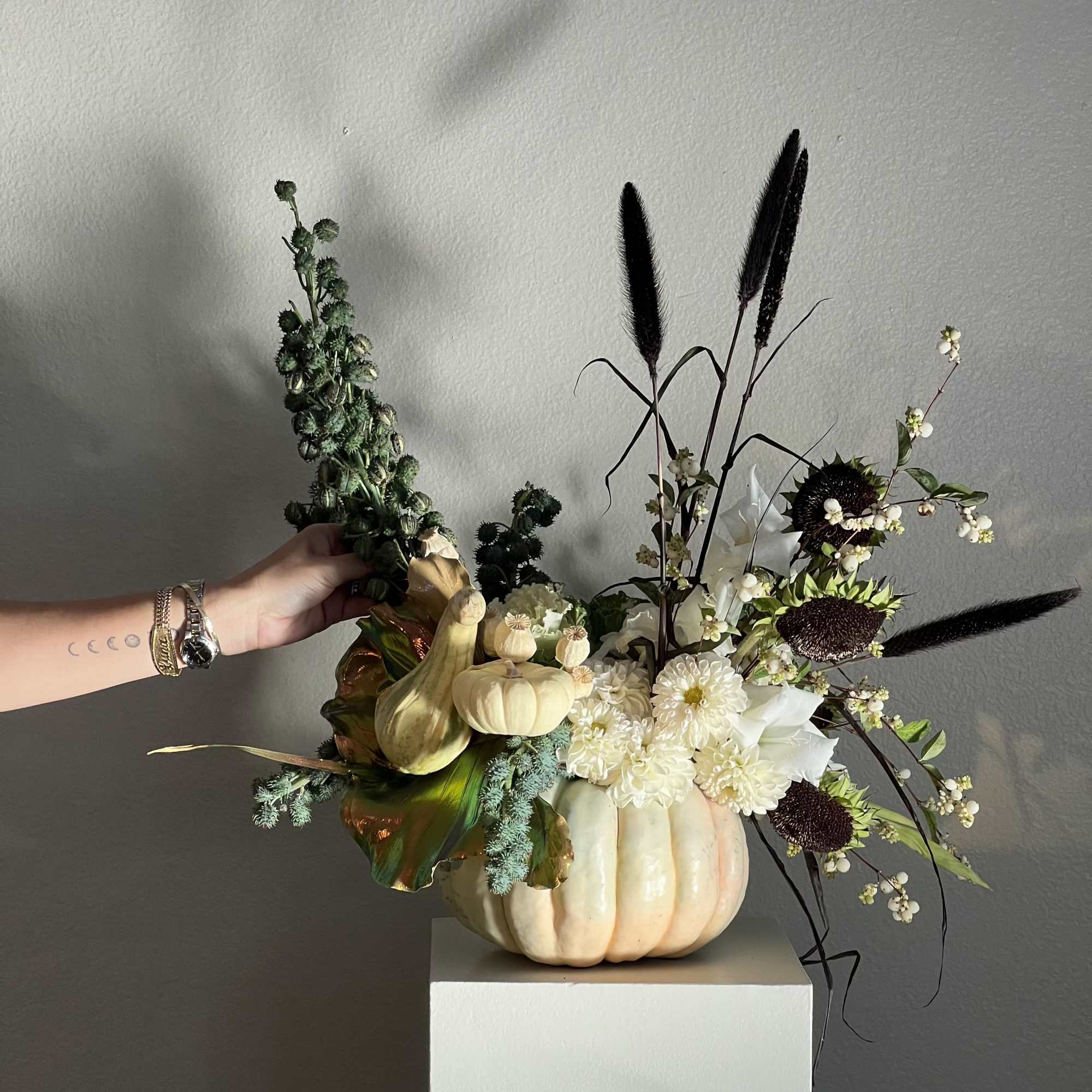 Pumpkin arrangement with white flowers and dark dried stems