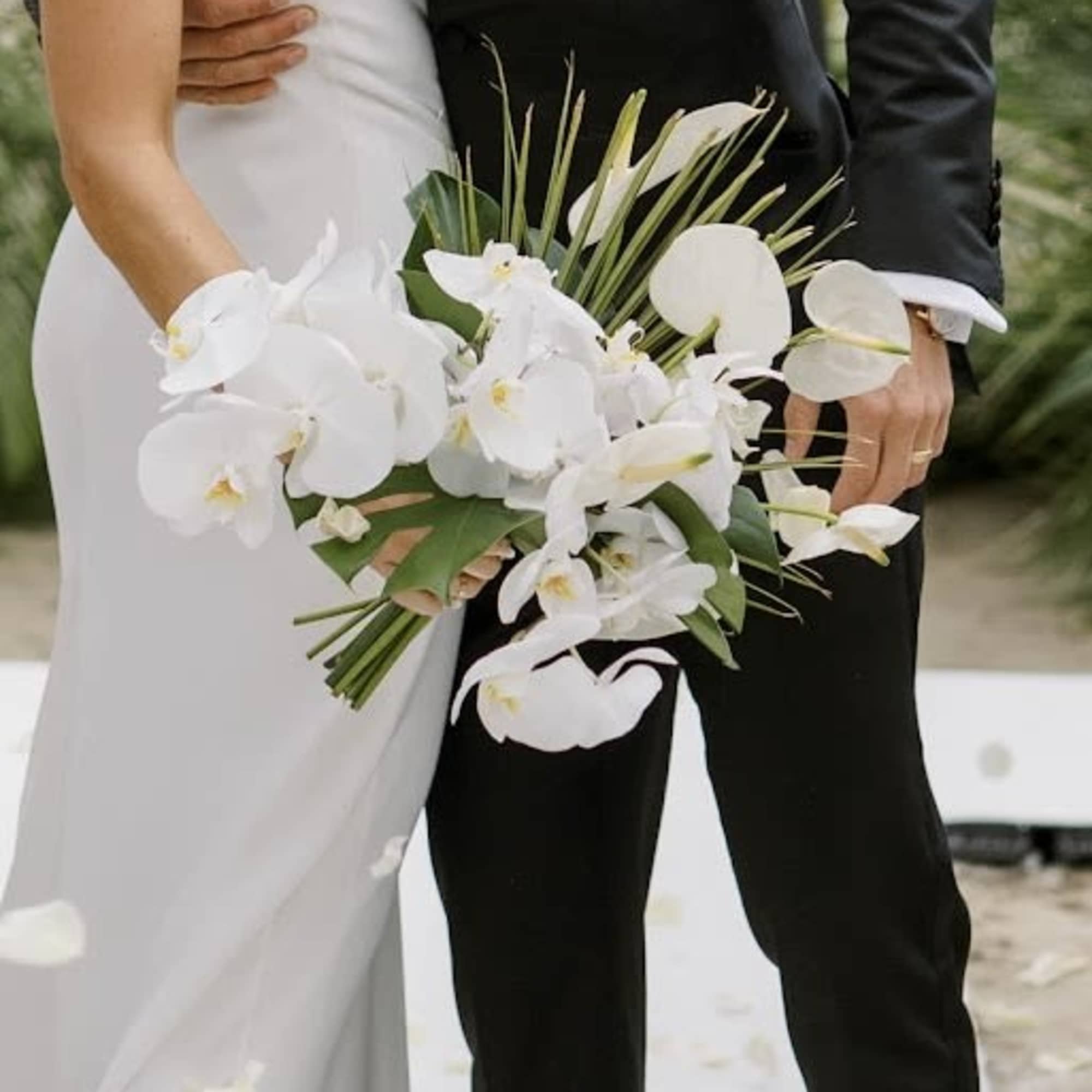 Bride and groom holding a white orchid wedding bouquet
