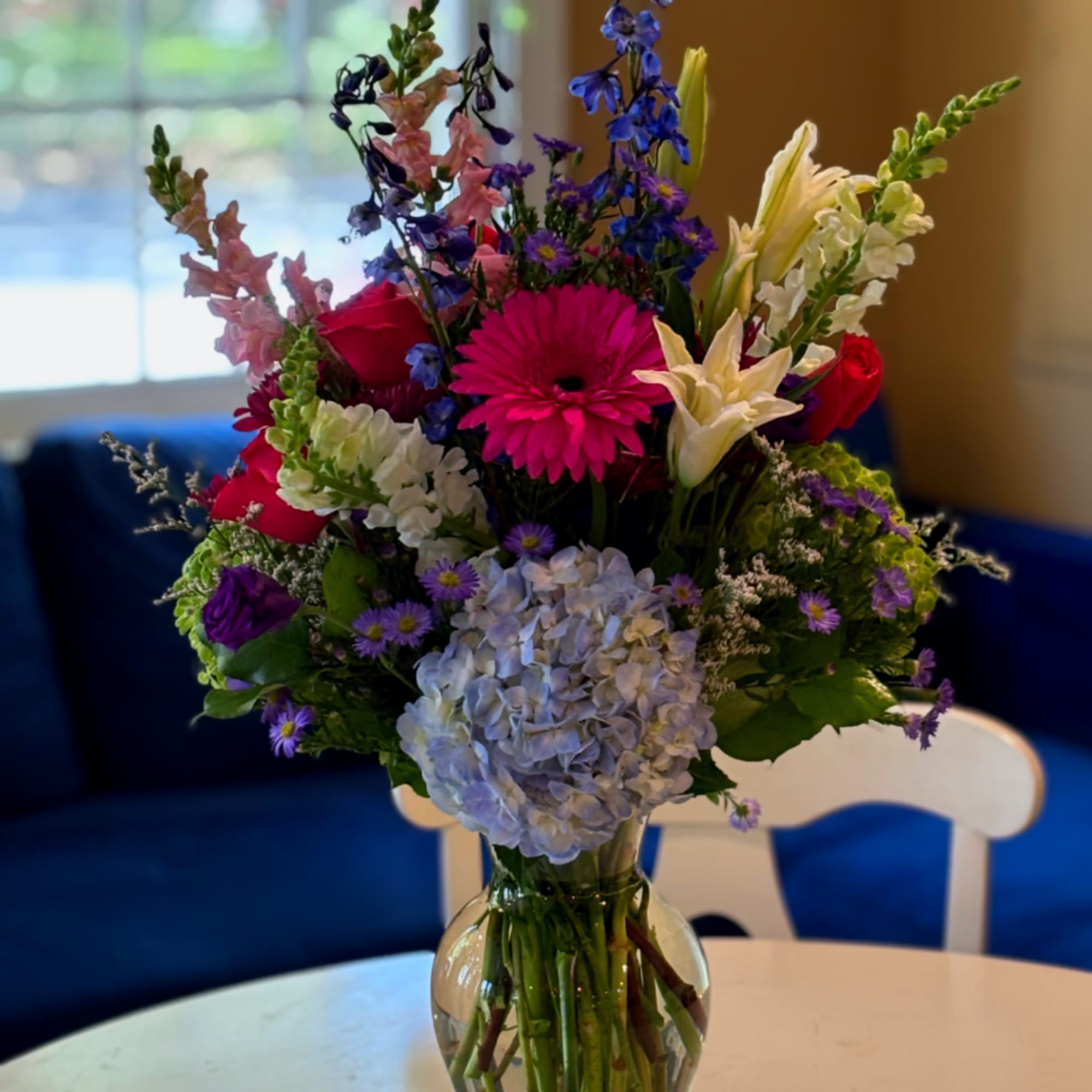 Mixed bouquet in a clear glass vase with pink, purple, white, and blue flowers