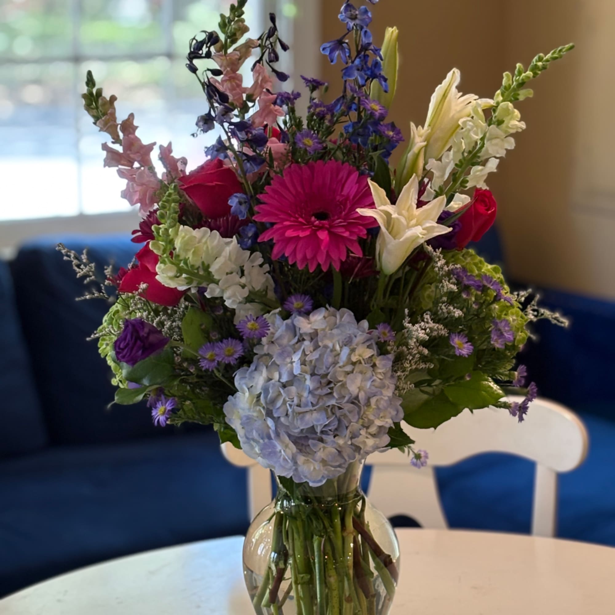 Mixed bouquet in a clear glass vase with pink, white, purple, and blue flowers