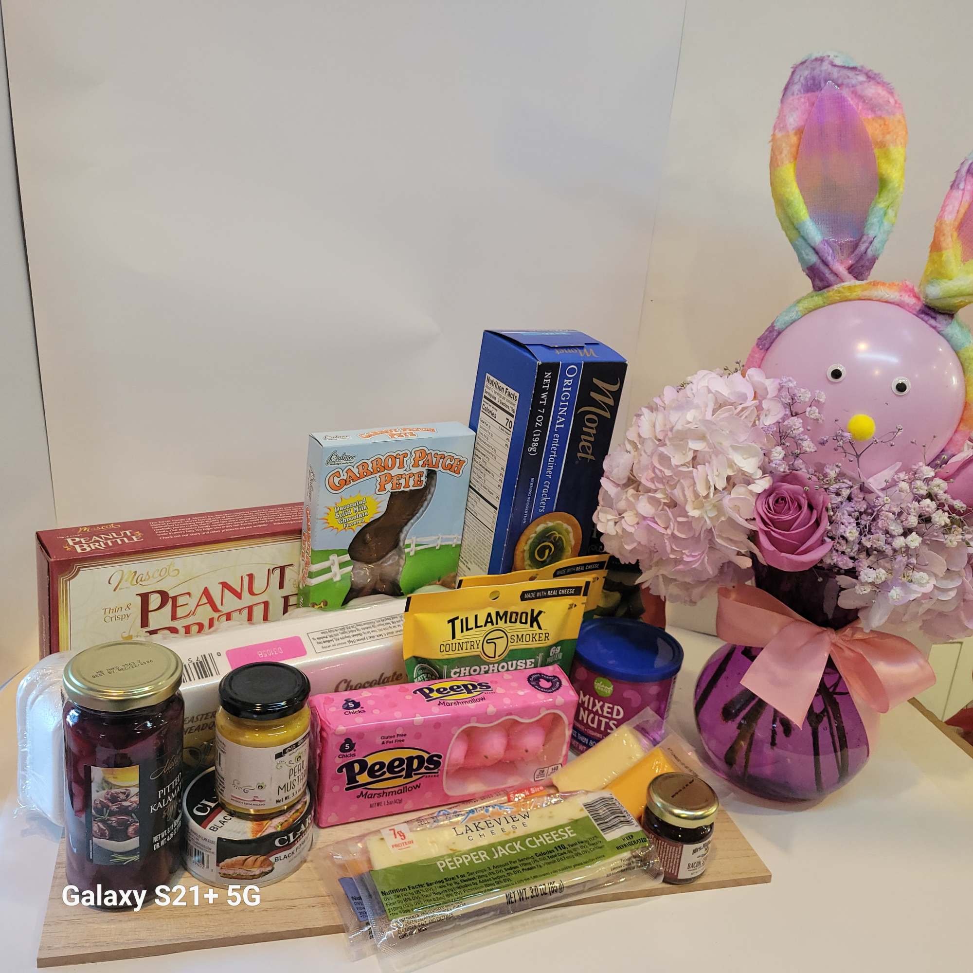 Gift basket with flowers, candy, and snacks beside a bunny decoration