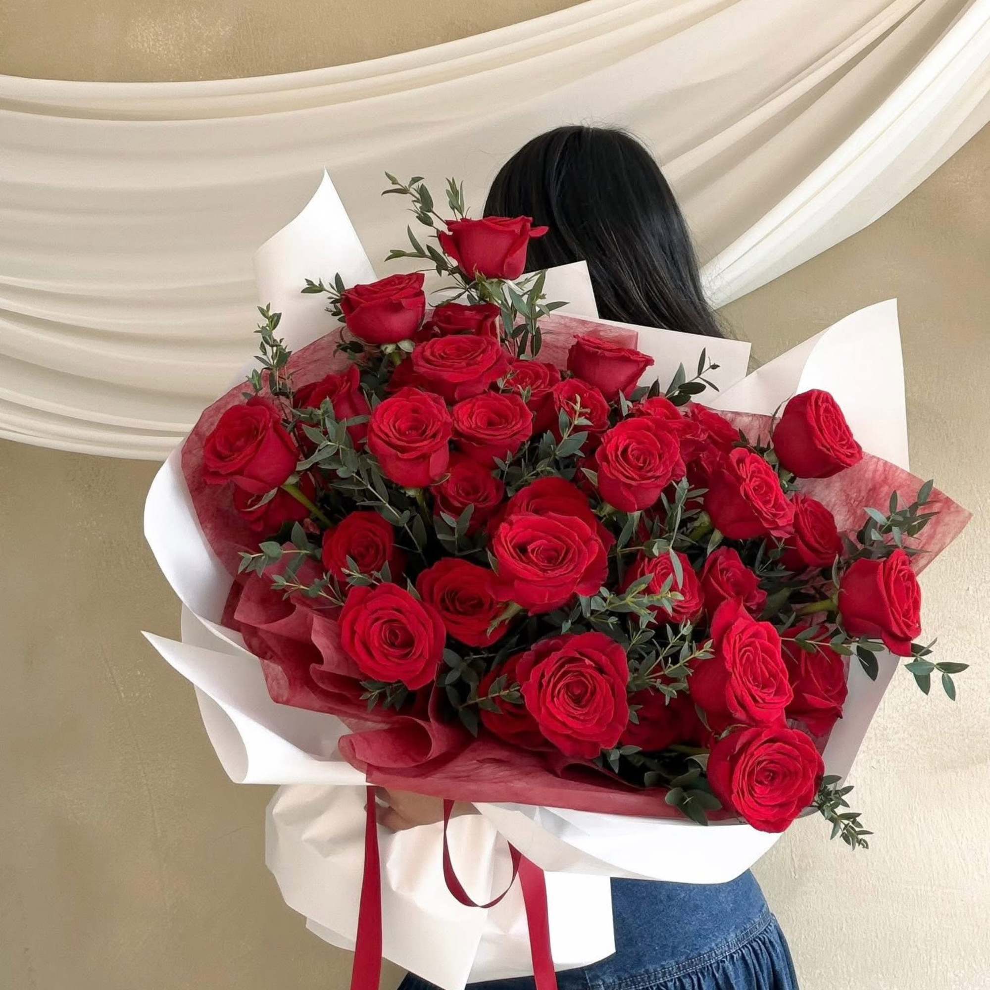 Large bouquet of red roses wrapped in white and red paper