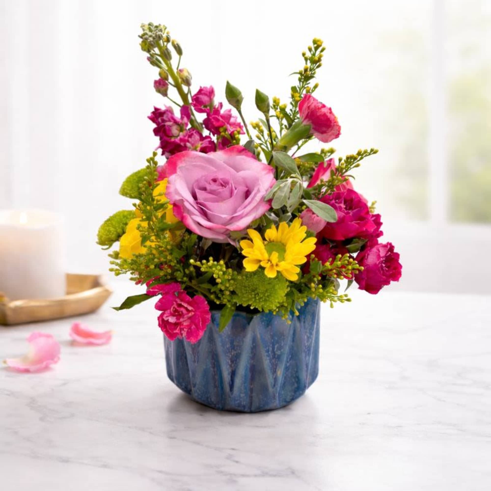 Pink and yellow flower arrangement in a blue ceramic pot