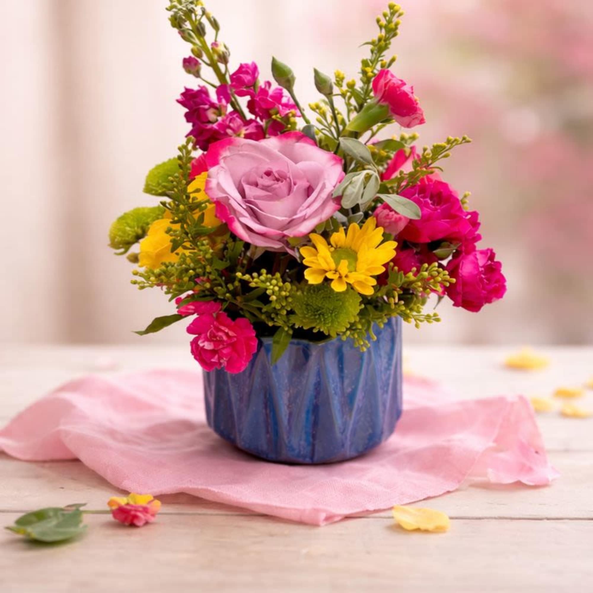 Pink and yellow mixed flower arrangement in a blue vase