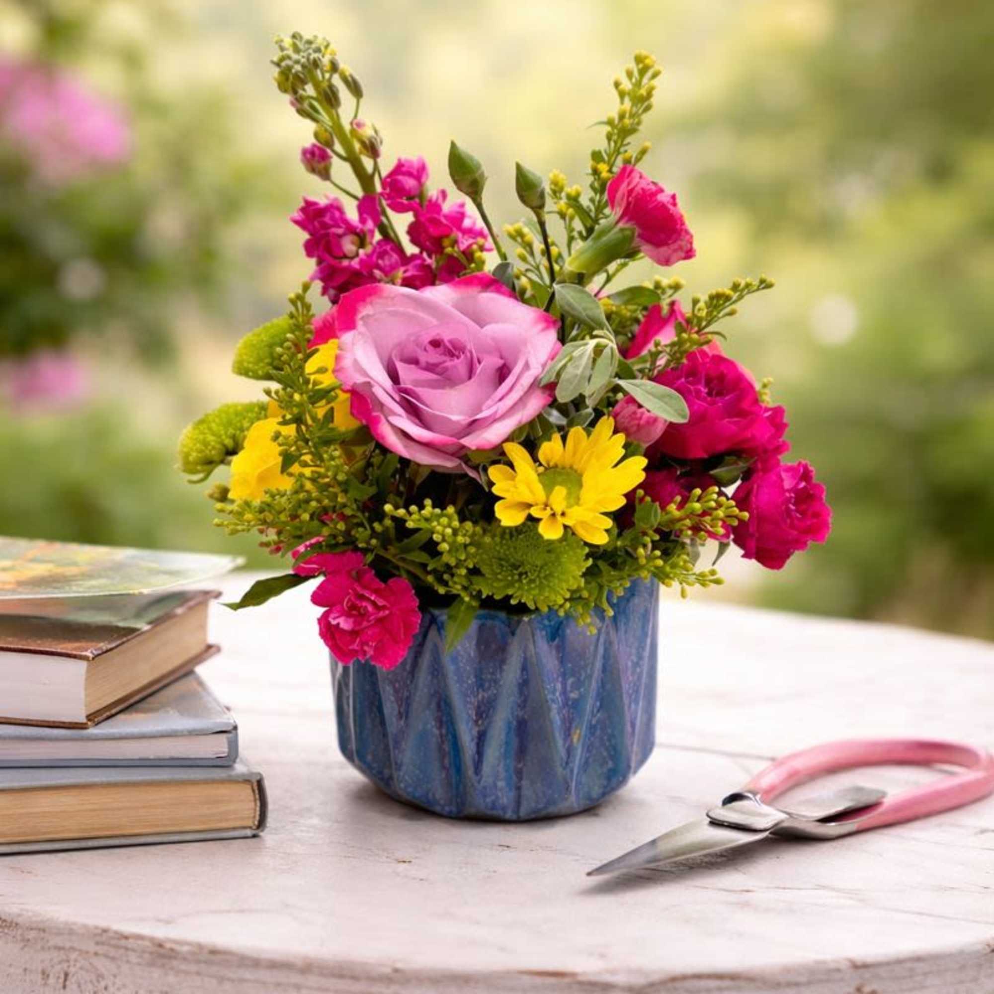 Pink and yellow mixed bouquet in a blue vase on a table