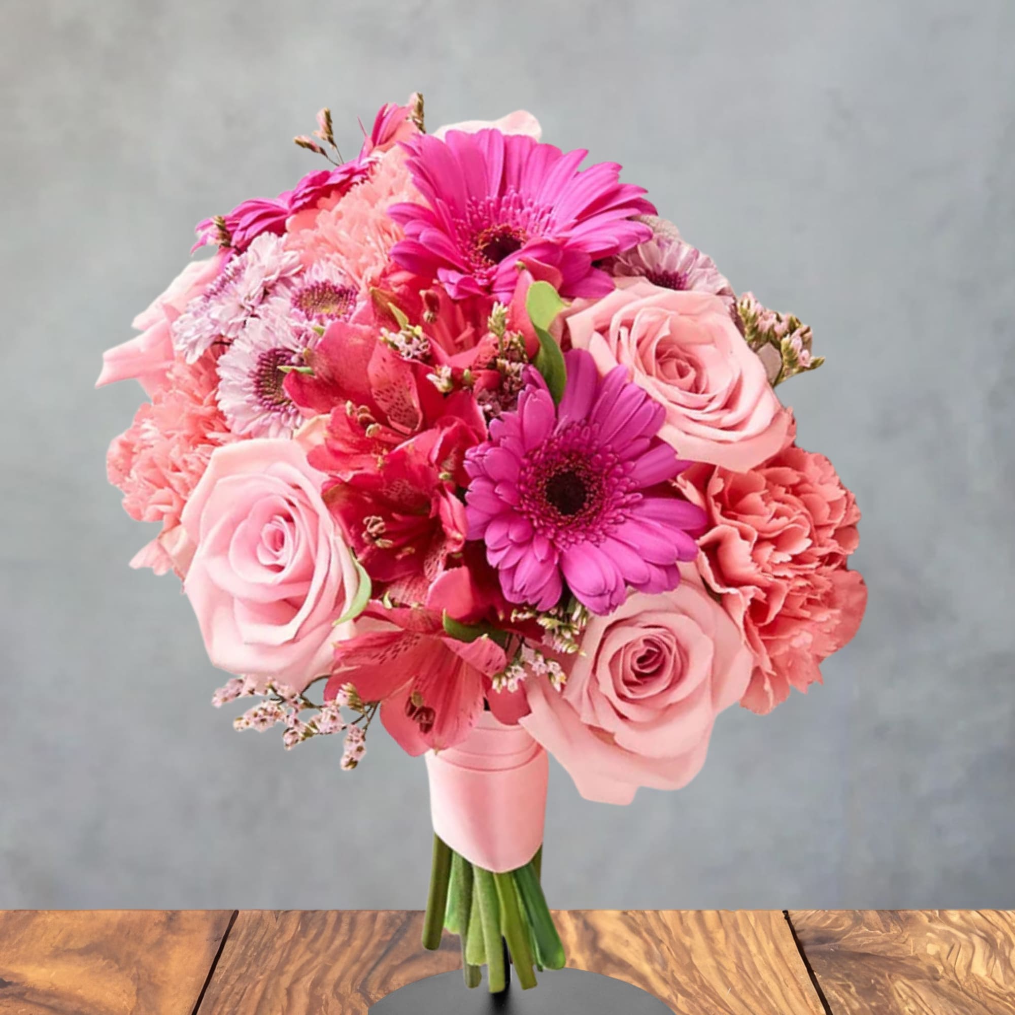 Pink bouquet of roses, gerbera daisies, and carnations on a stand