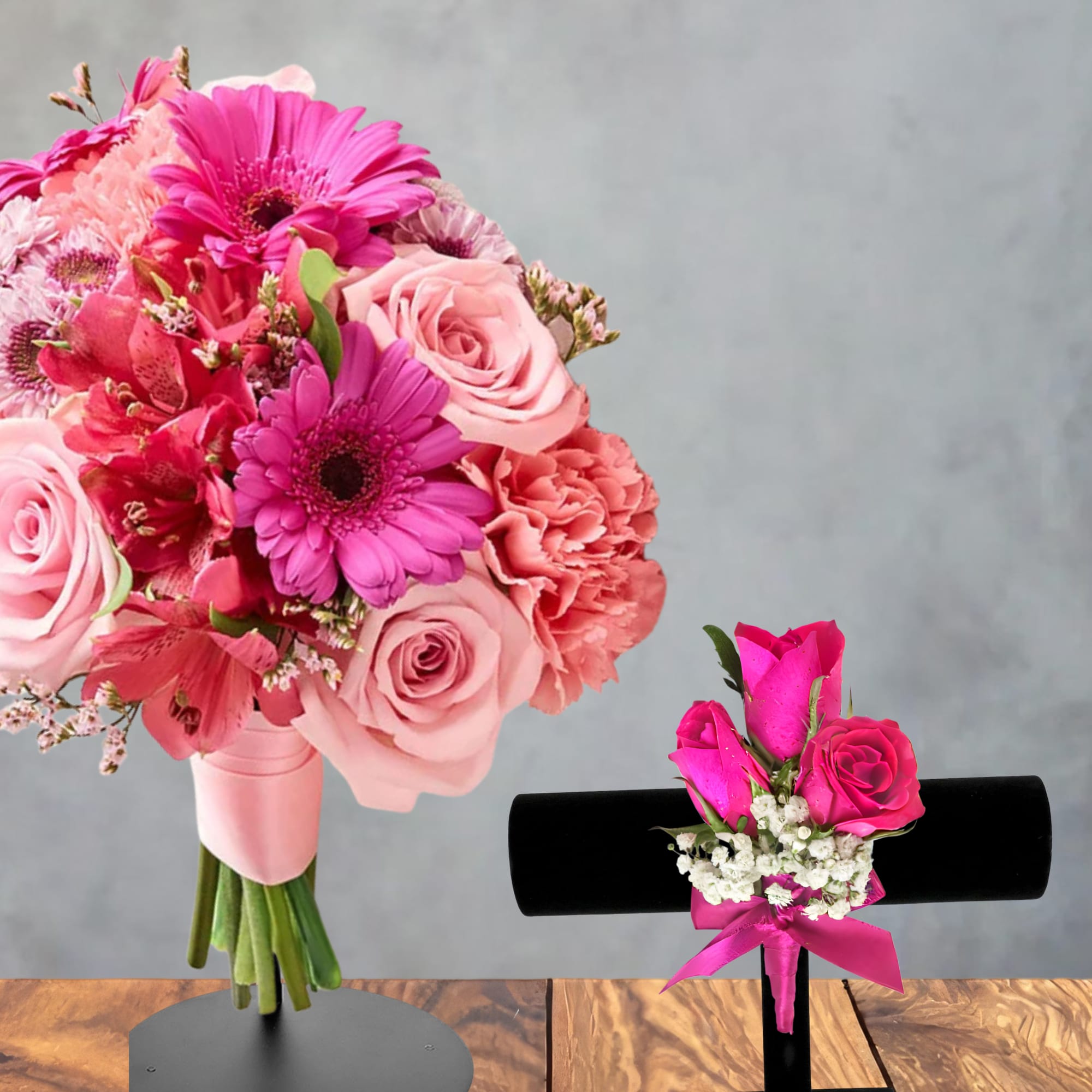 Pink bouquet with roses, gerbera daisies, and carnations beside a small corsage.