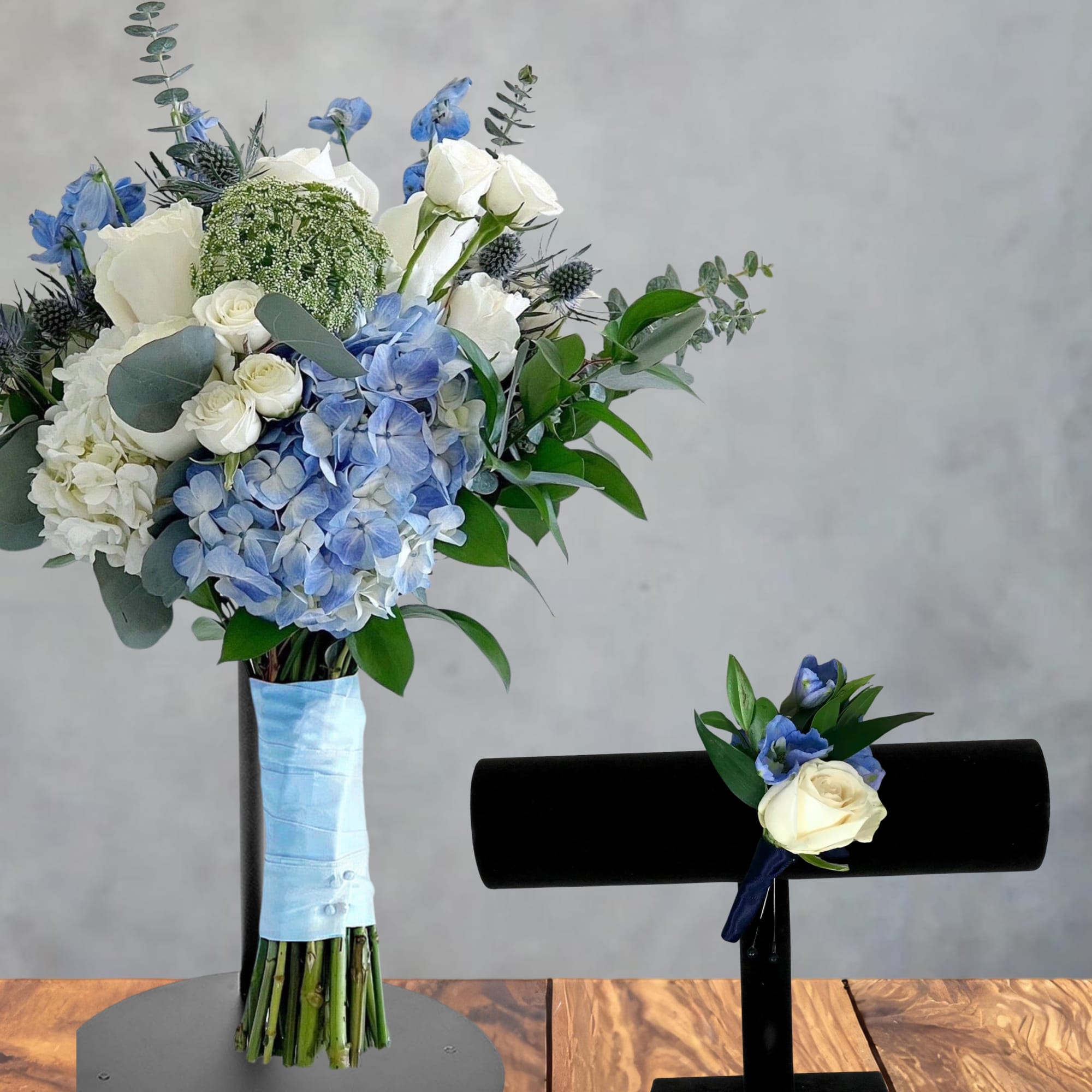 Blue and white floral bouquet with a matching boutonniere on display stands