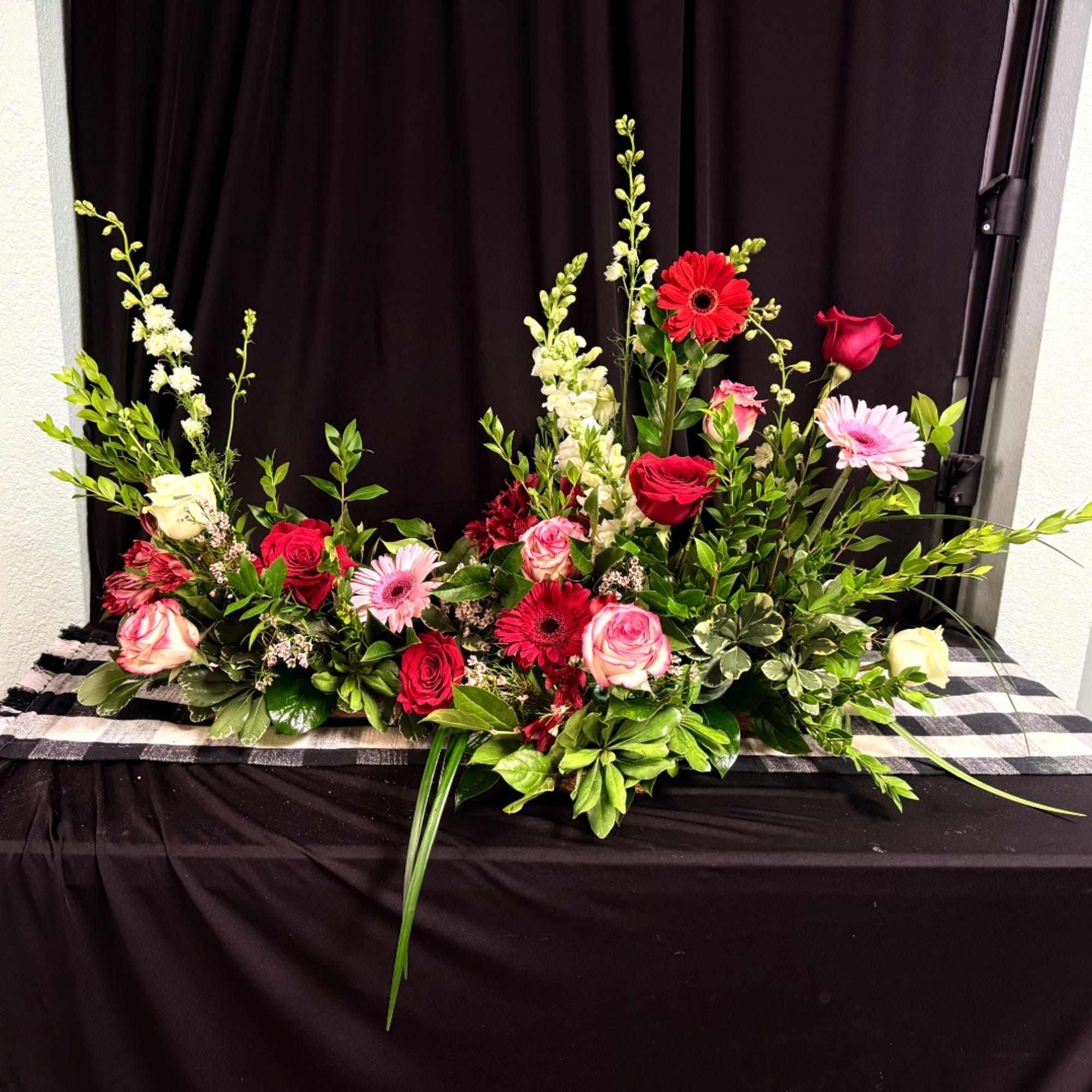 Long floral arrangement with red and pink roses and gerbera daisies