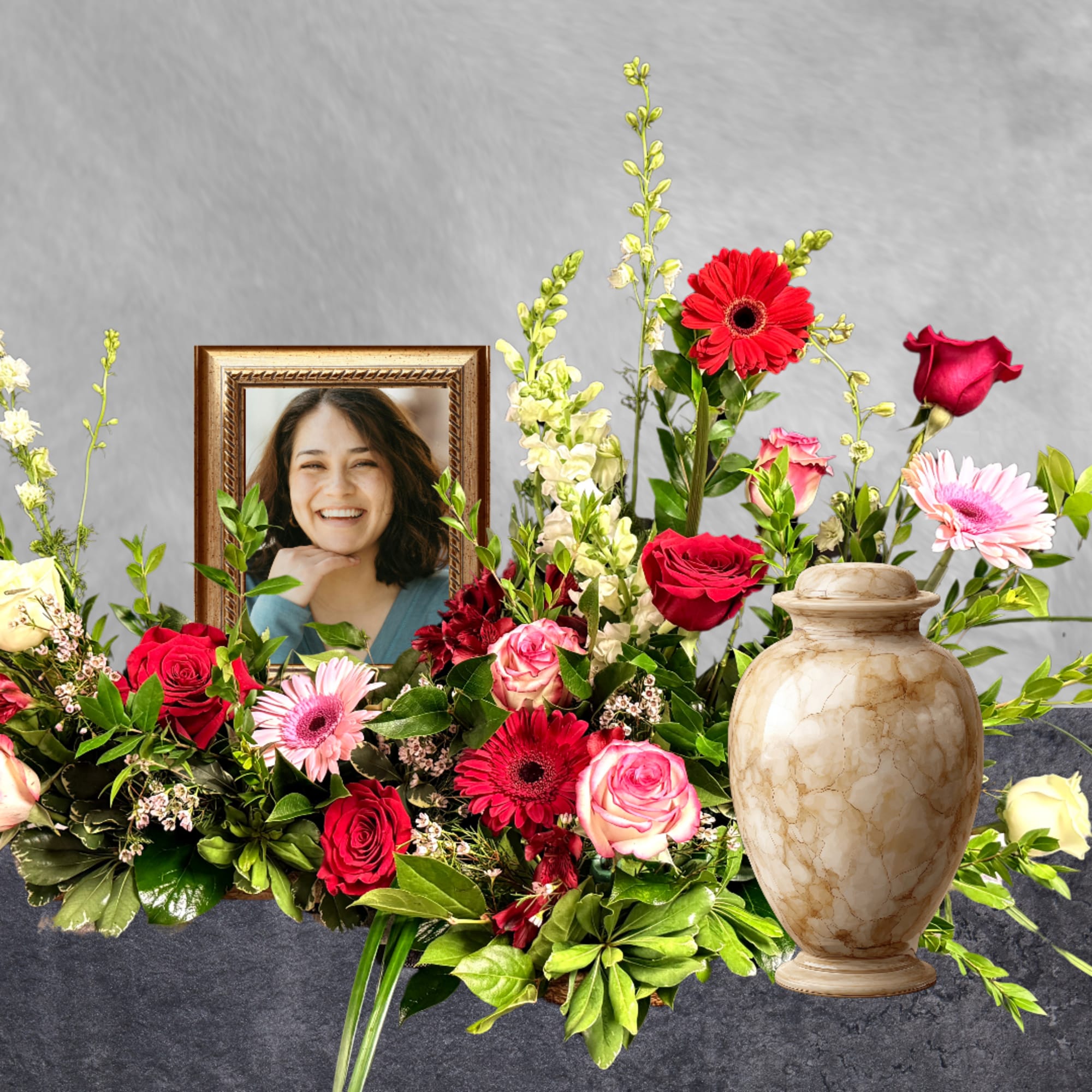 Floral tribute with red and pink roses, gerbera daisies, and a framed portrait
