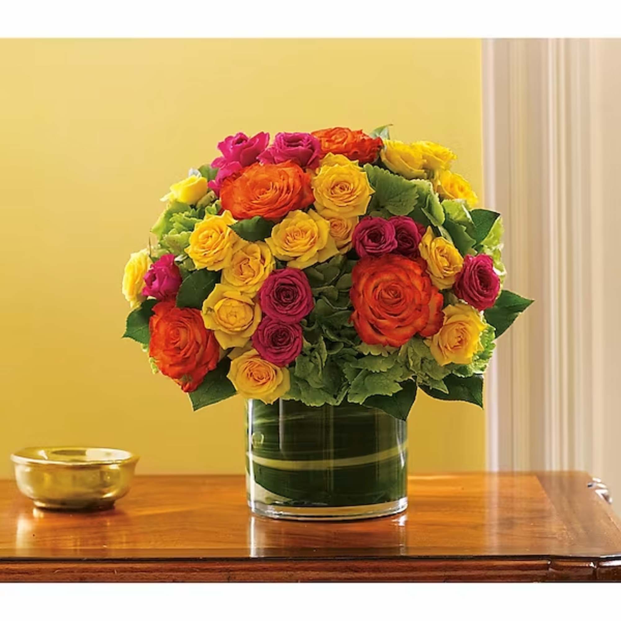 Bouquet of yellow, orange, and pink roses in a glass vase