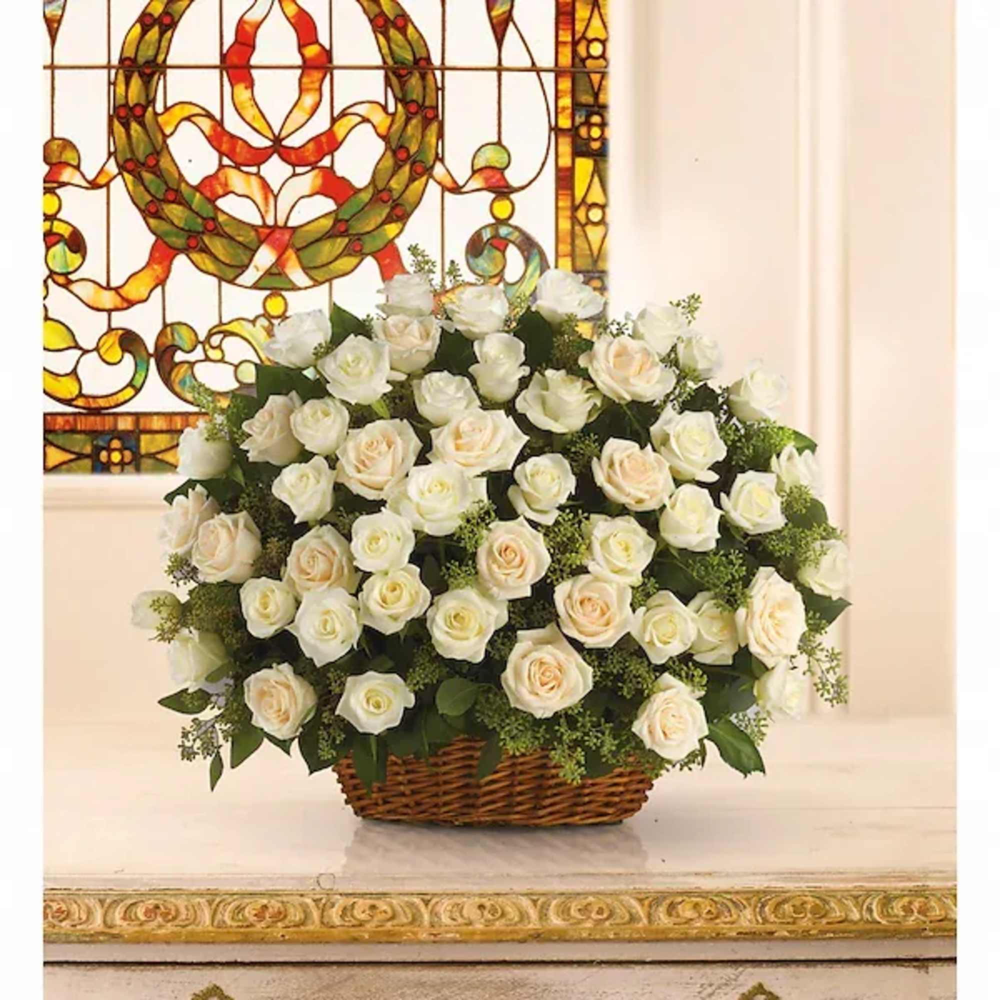 Basket of white roses arranged in front of a stained-glass window