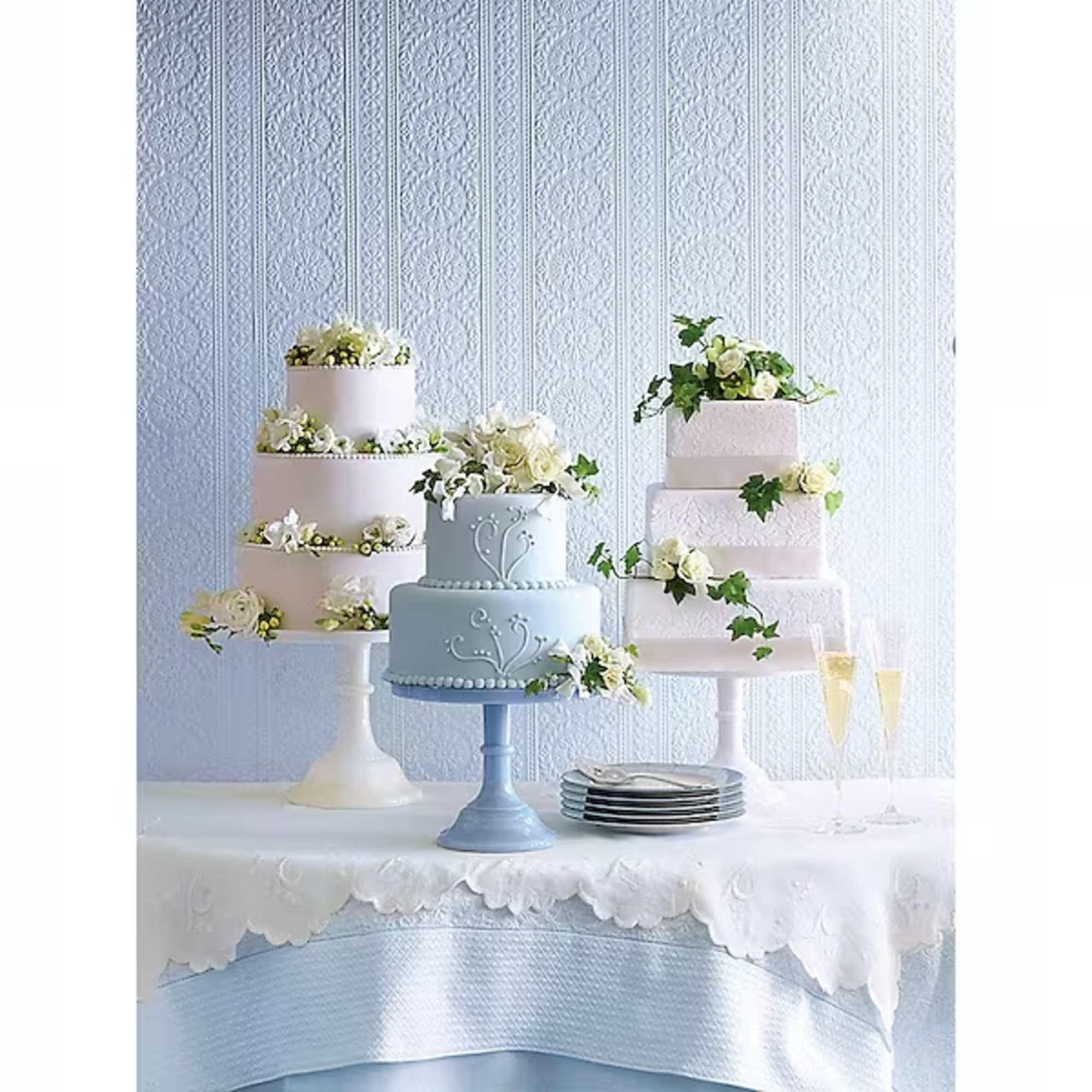 Three tiered cakes decorated with white flowers on pedestals