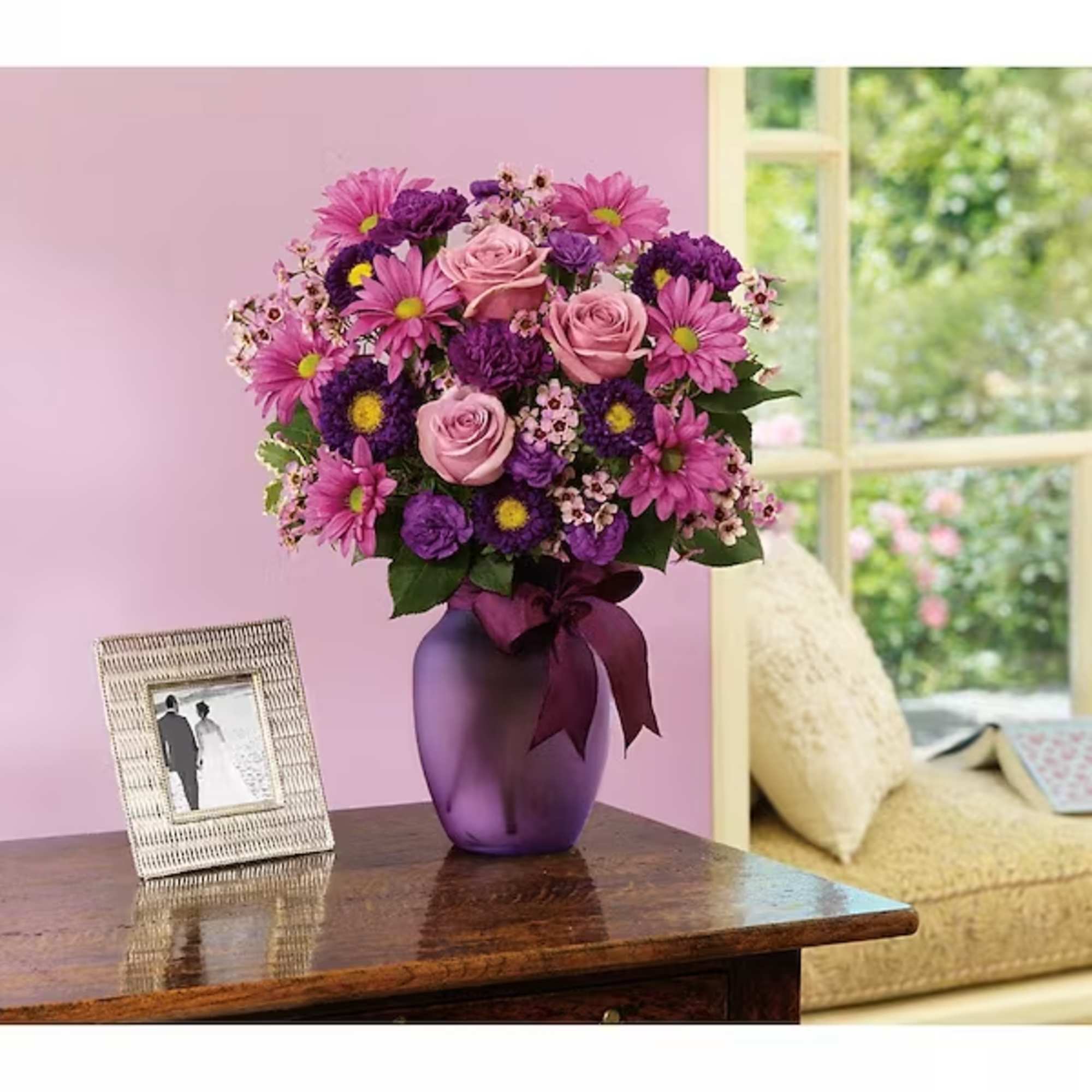 Pink and purple bouquet in a purple vase on a table