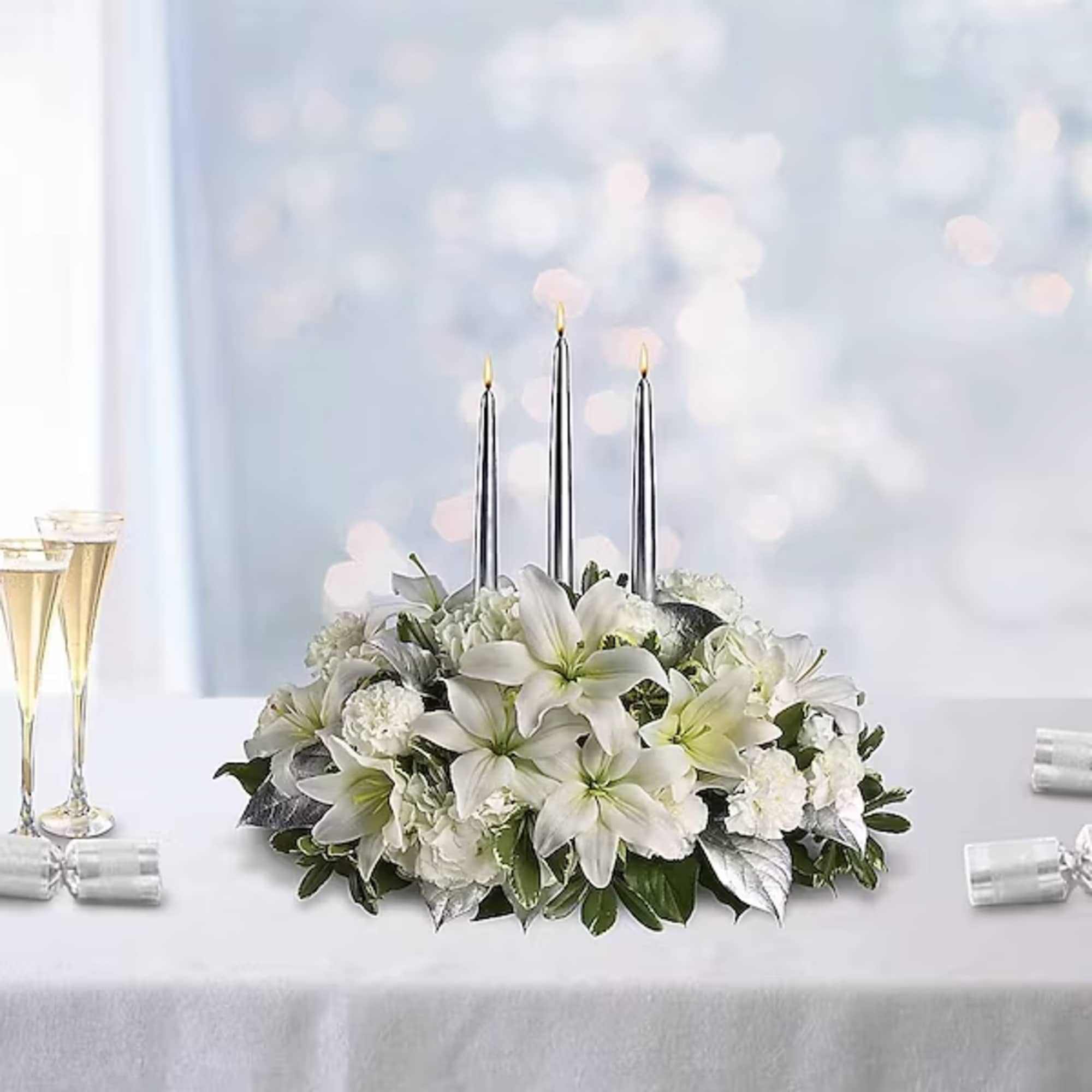 White floral centerpiece with three silver taper candles