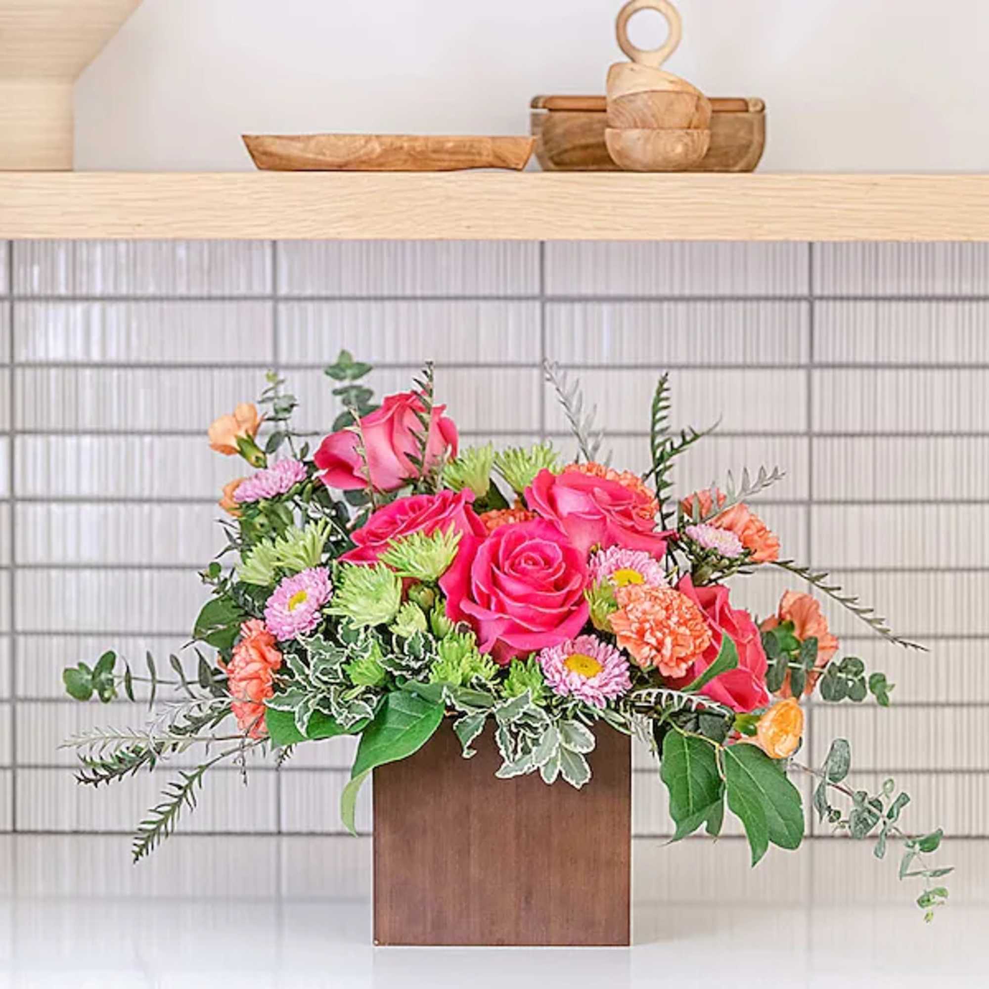 Pink roses and mixed flowers arranged in a wooden box