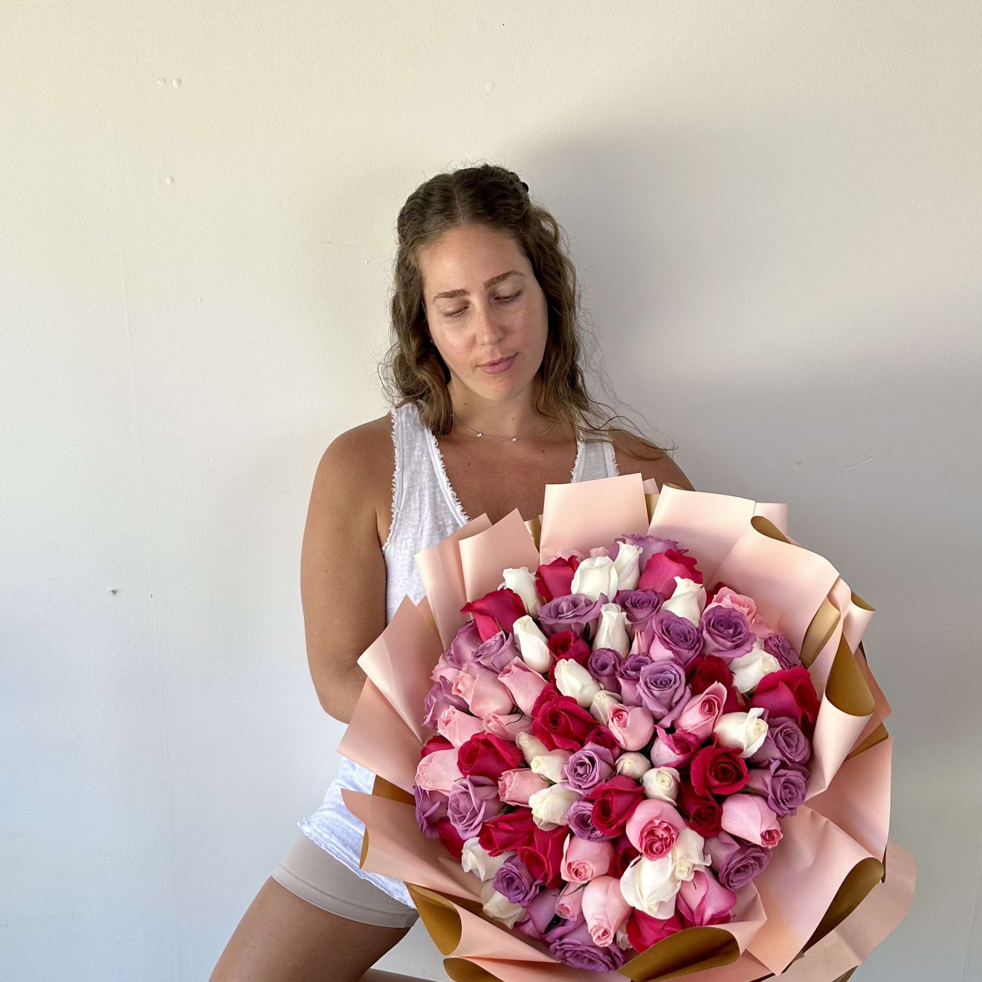 Woman holding a large bouquet of pink, red, white, and lavender roses