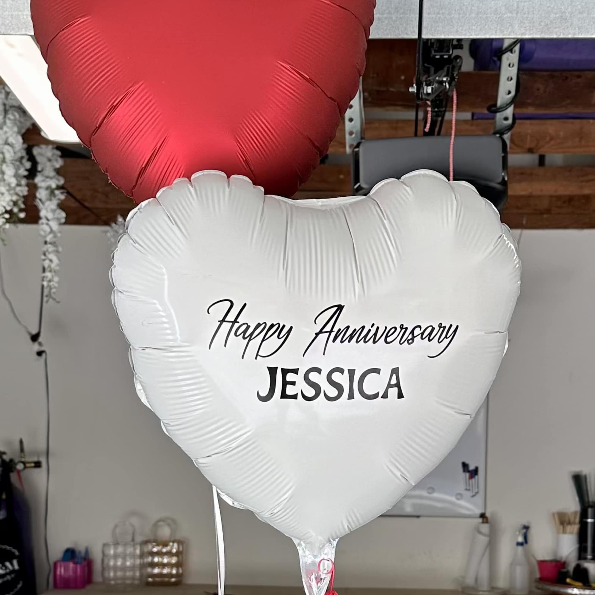 Heart-shaped anniversary balloons in red and white with personalized text