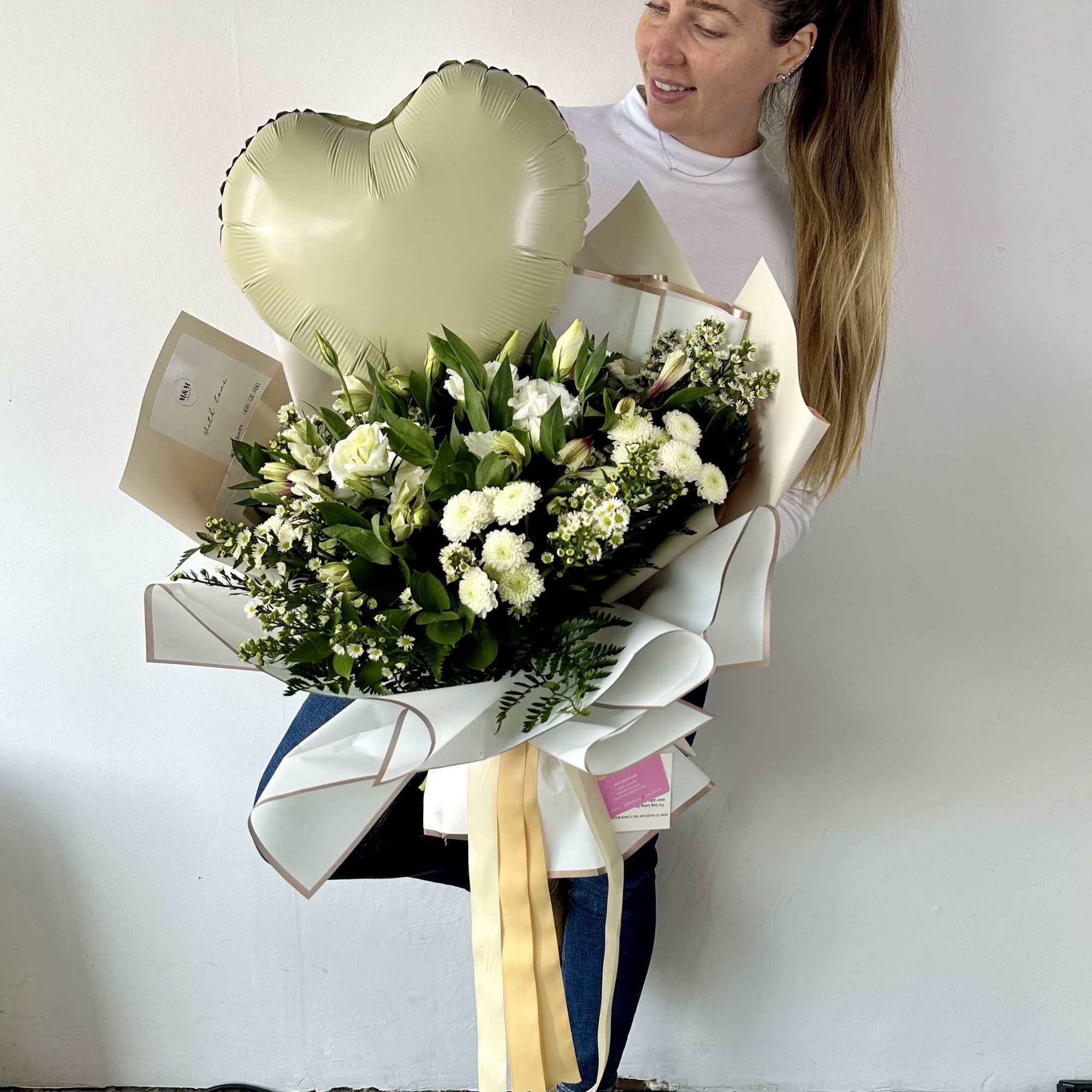 Woman holding a large white flower bouquet with a heart balloon