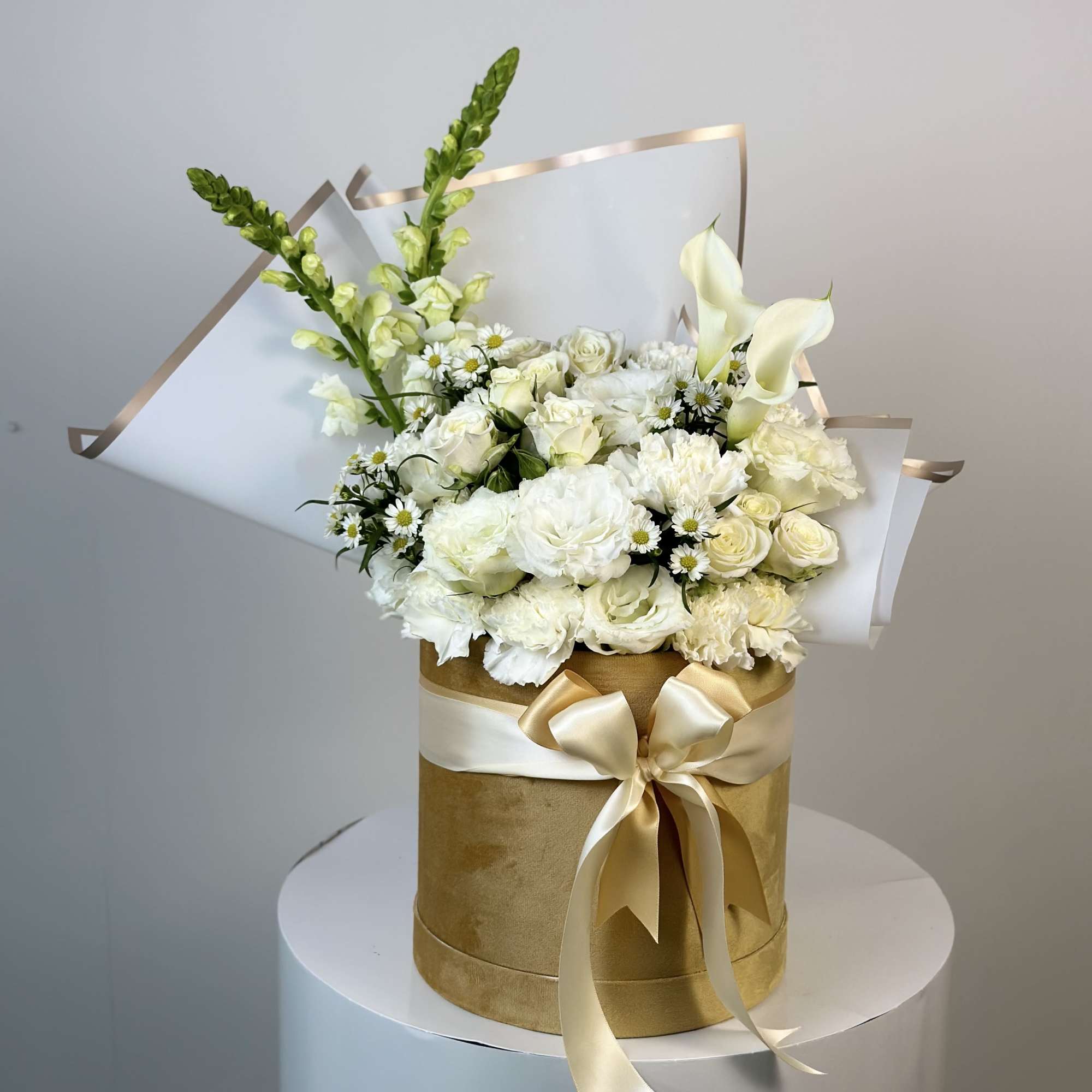 White floral bouquet in a gold hatbox with a satin bow
