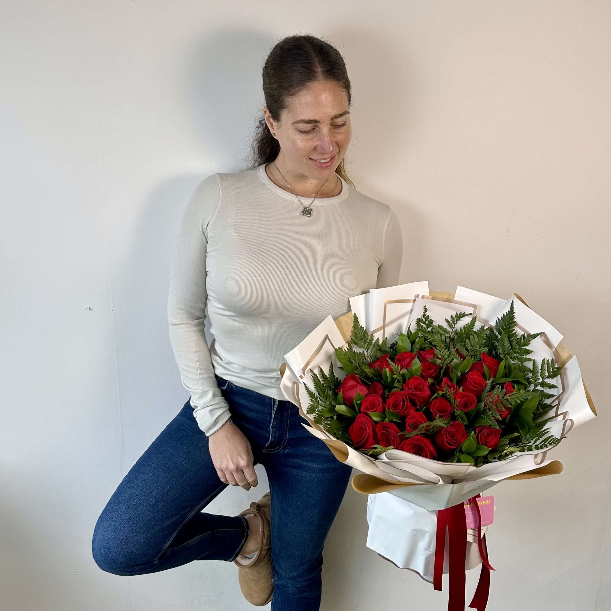 Woman holding a large bouquet of red roses wrapped in white paper, photo 2 of 2